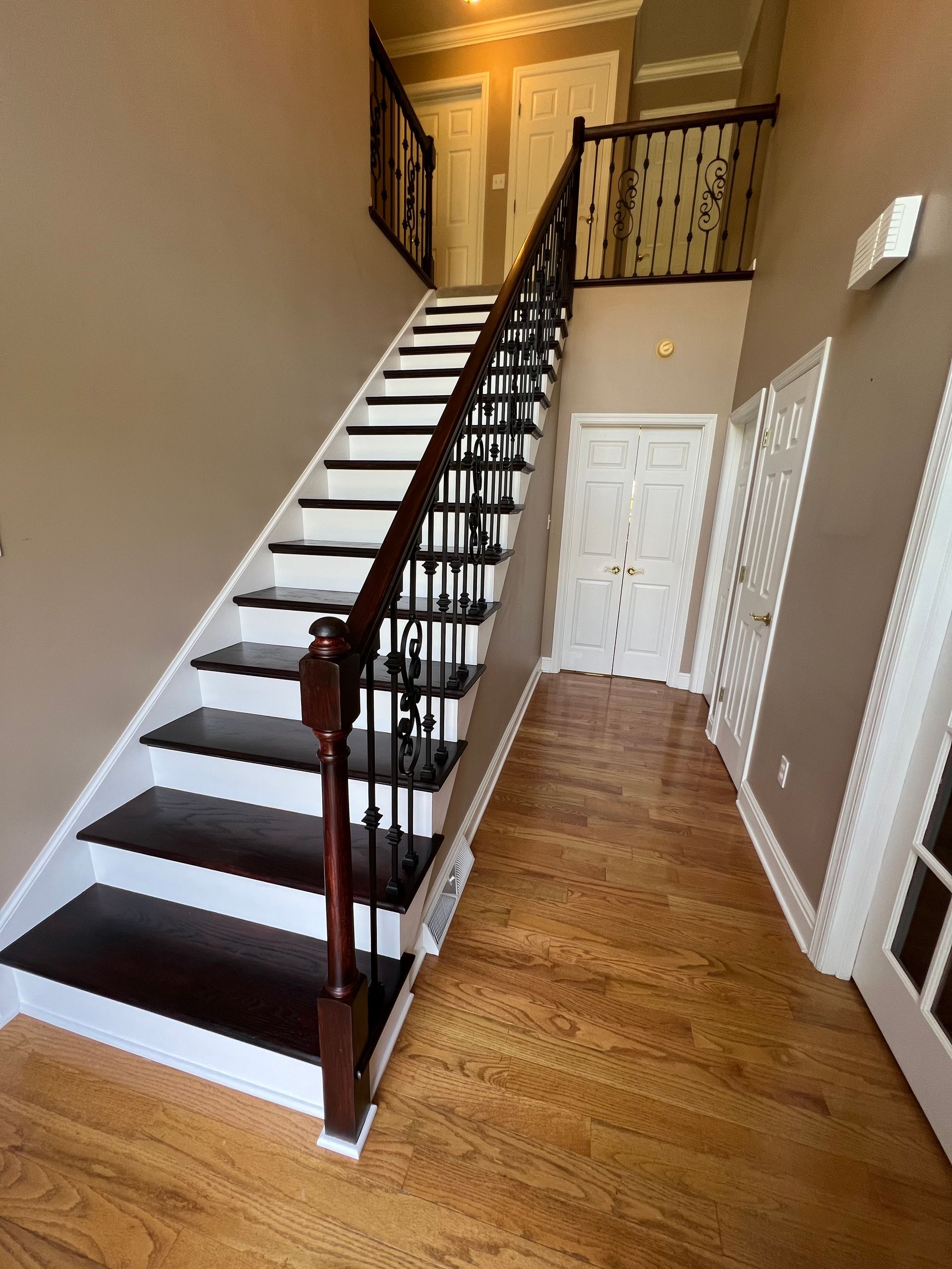 A staircase in a hallway with wooden floors and a wrought iron railing.