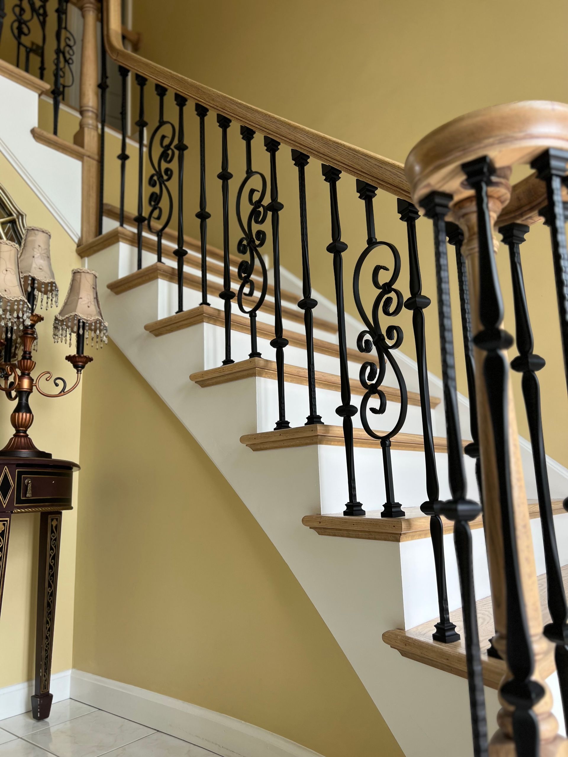 A wooden staircase with a wrought iron railing