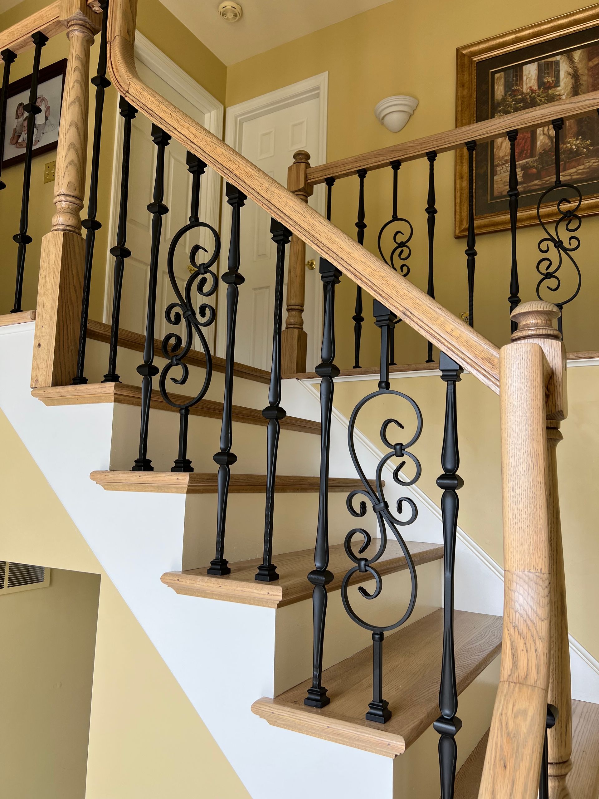 A staircase with a wrought iron railing and a wooden handrail
