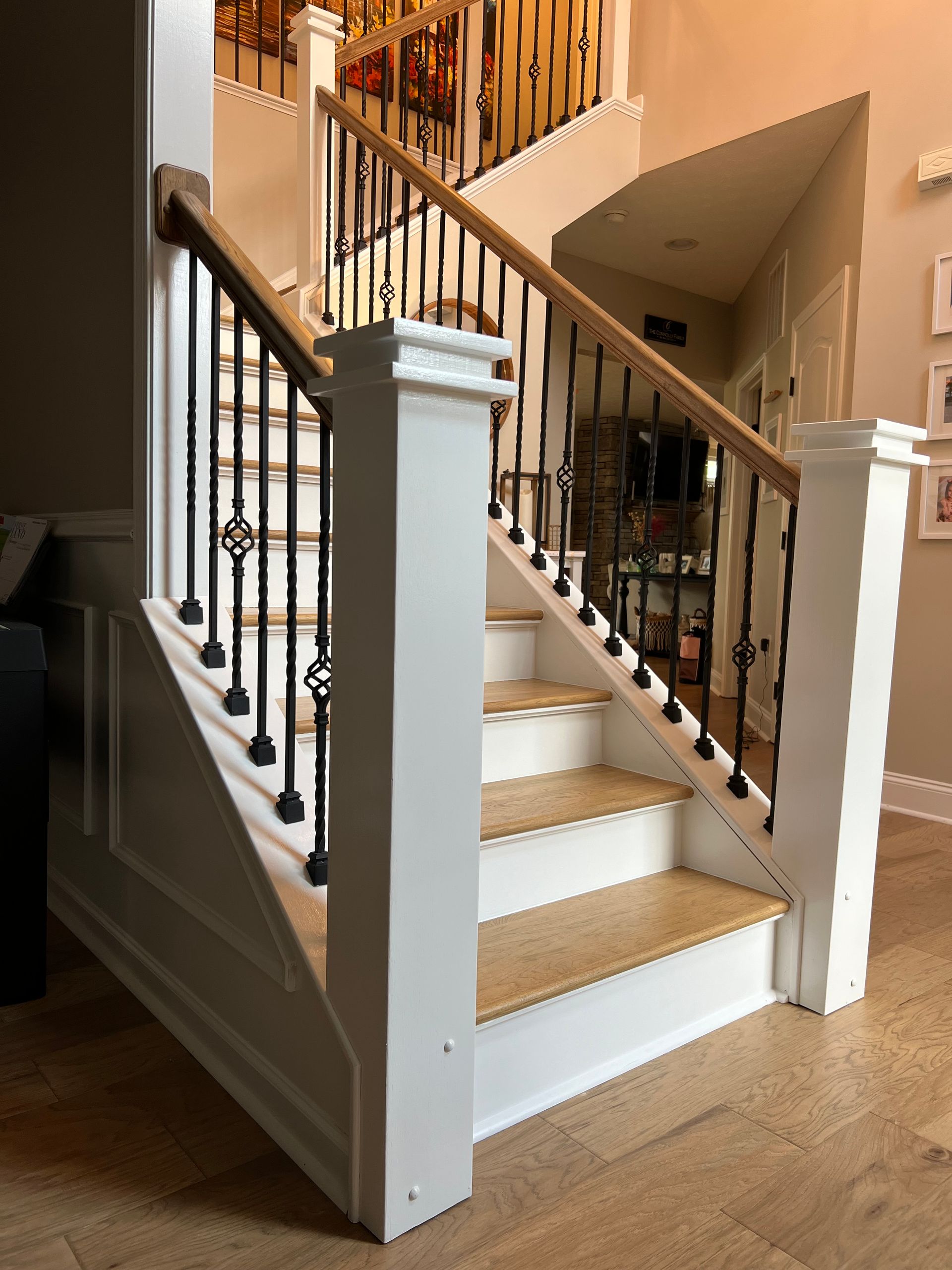 A white staircase with wooden steps and a black railing in a living room.
