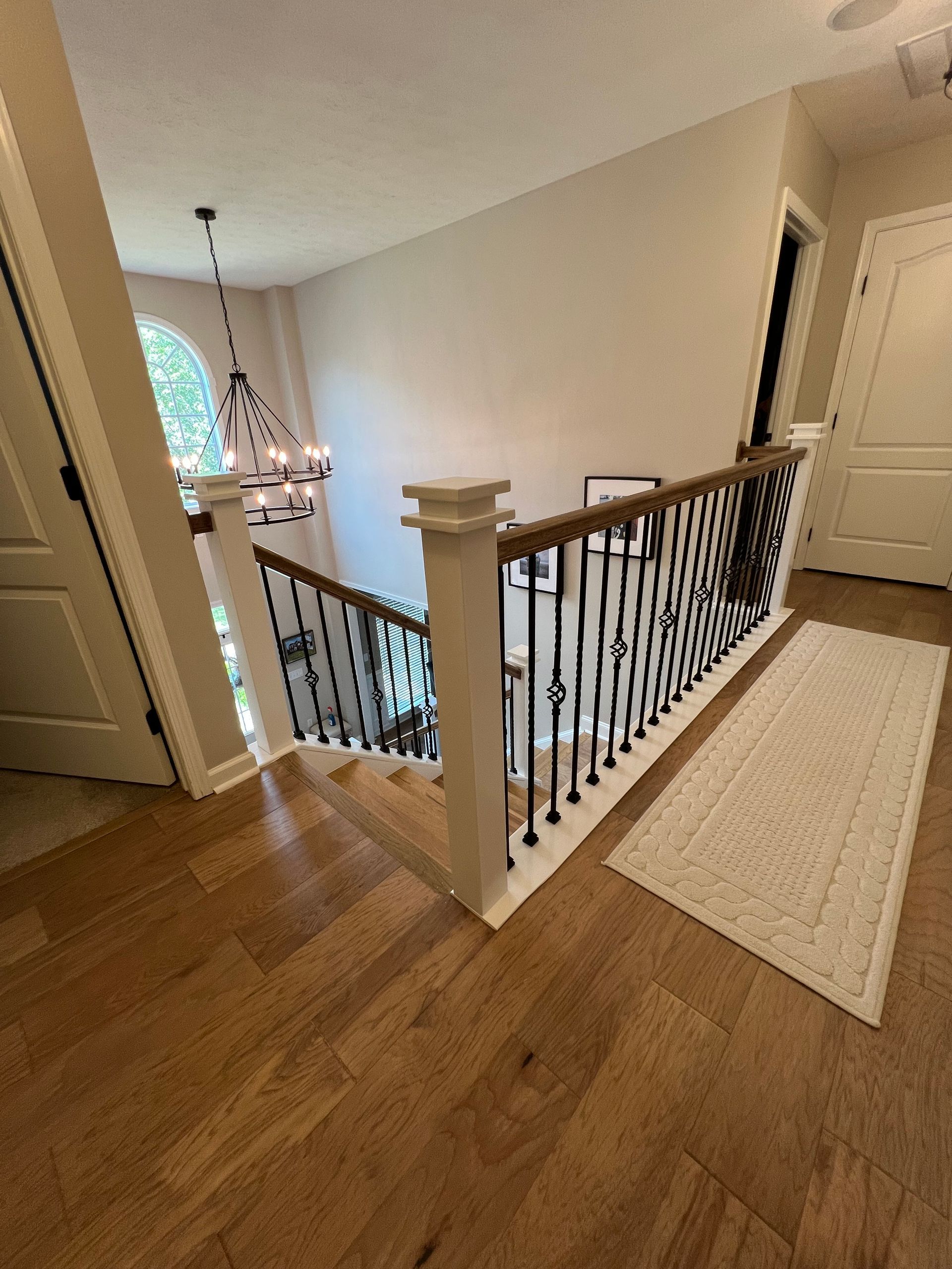 A staircase with a wrought iron railing and hardwood floors in a house.