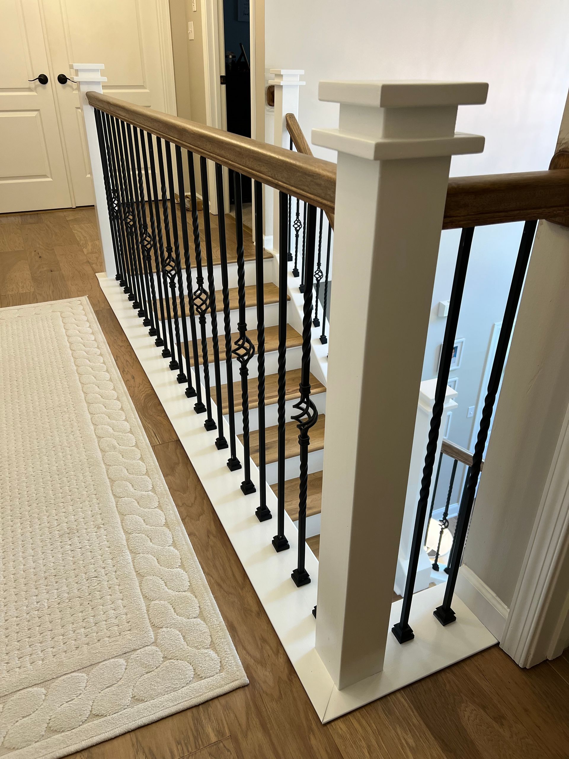 A staircase with a wrought iron railing and a wooden handrail.