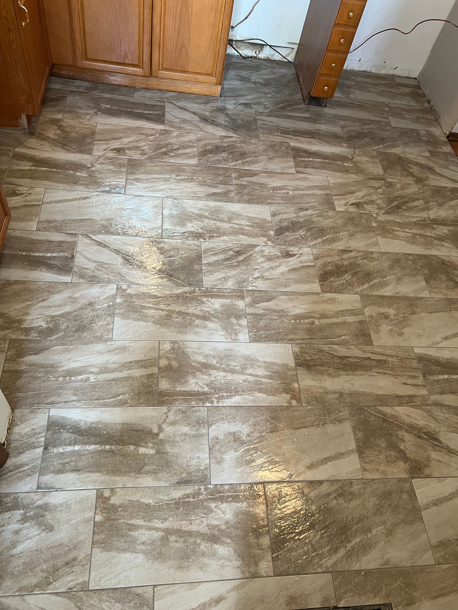 A kitchen with a tiled floor and wooden cabinets.