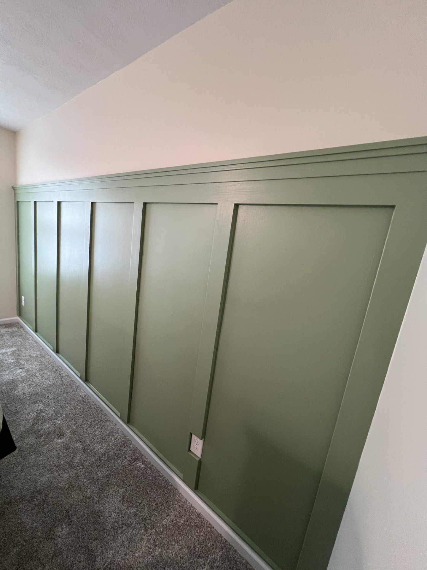 A room with green paneling on the wall and a carpeted floor.
