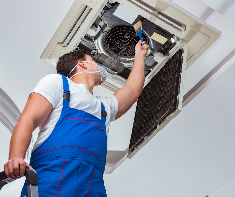A man wearing a mask is working on an air conditioner