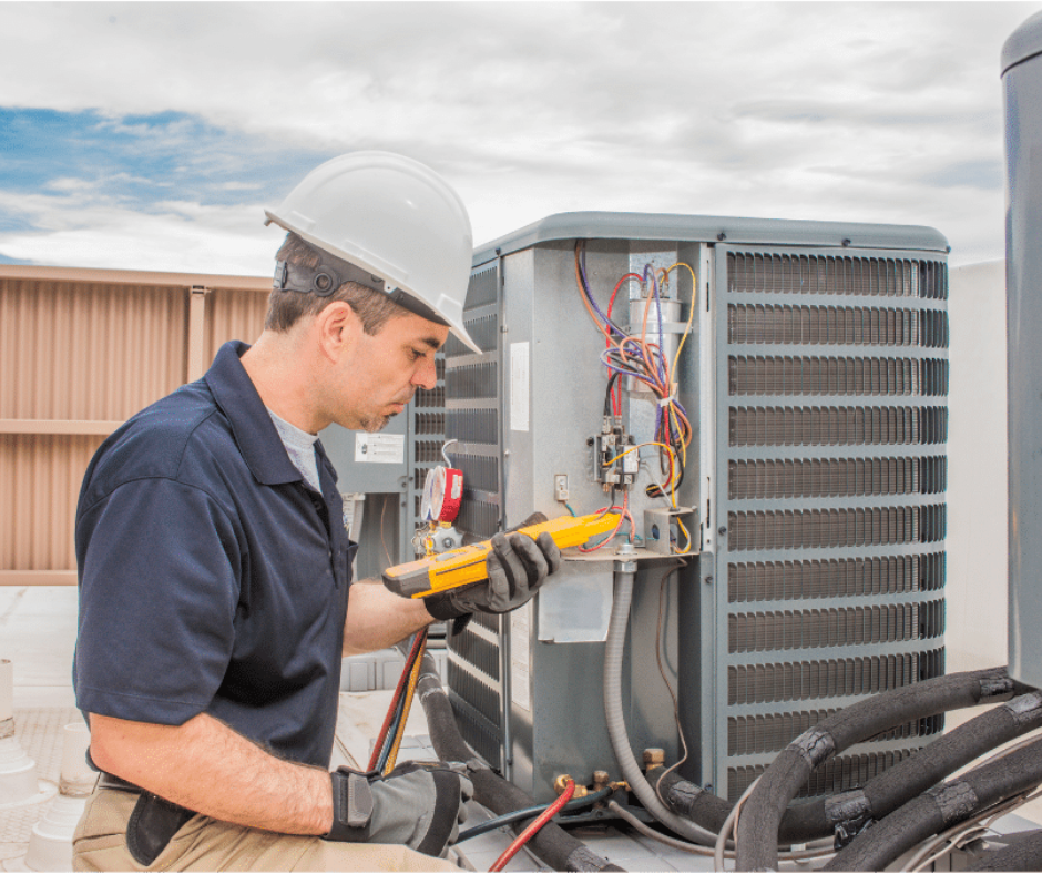 A man is working on an air conditioner on the roof of a building.