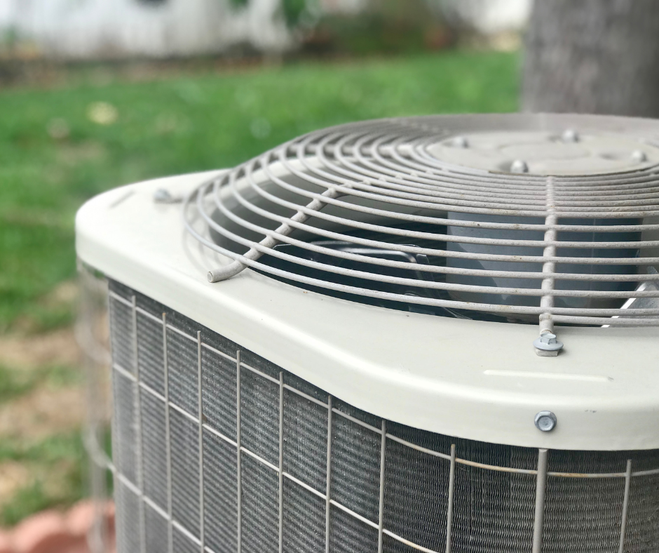 A close up of an air conditioner outside in the grass.