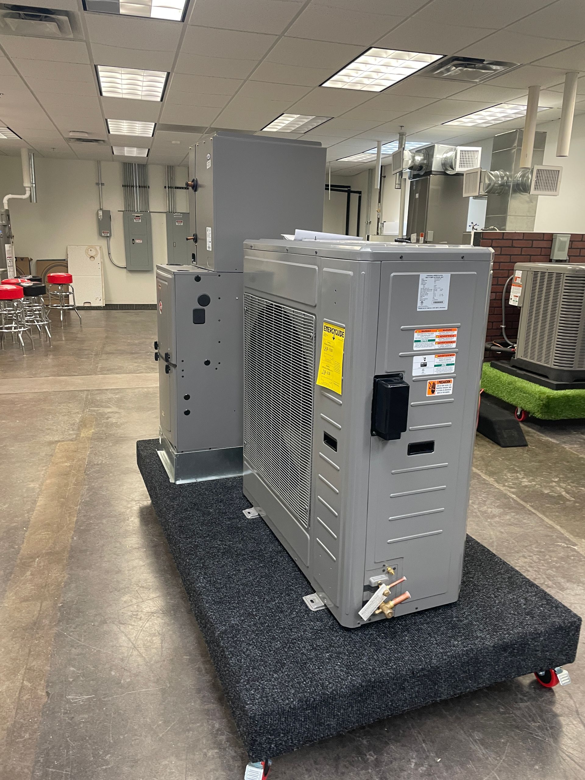 A white water heater is hanging on a white wall next to a copper pipe.