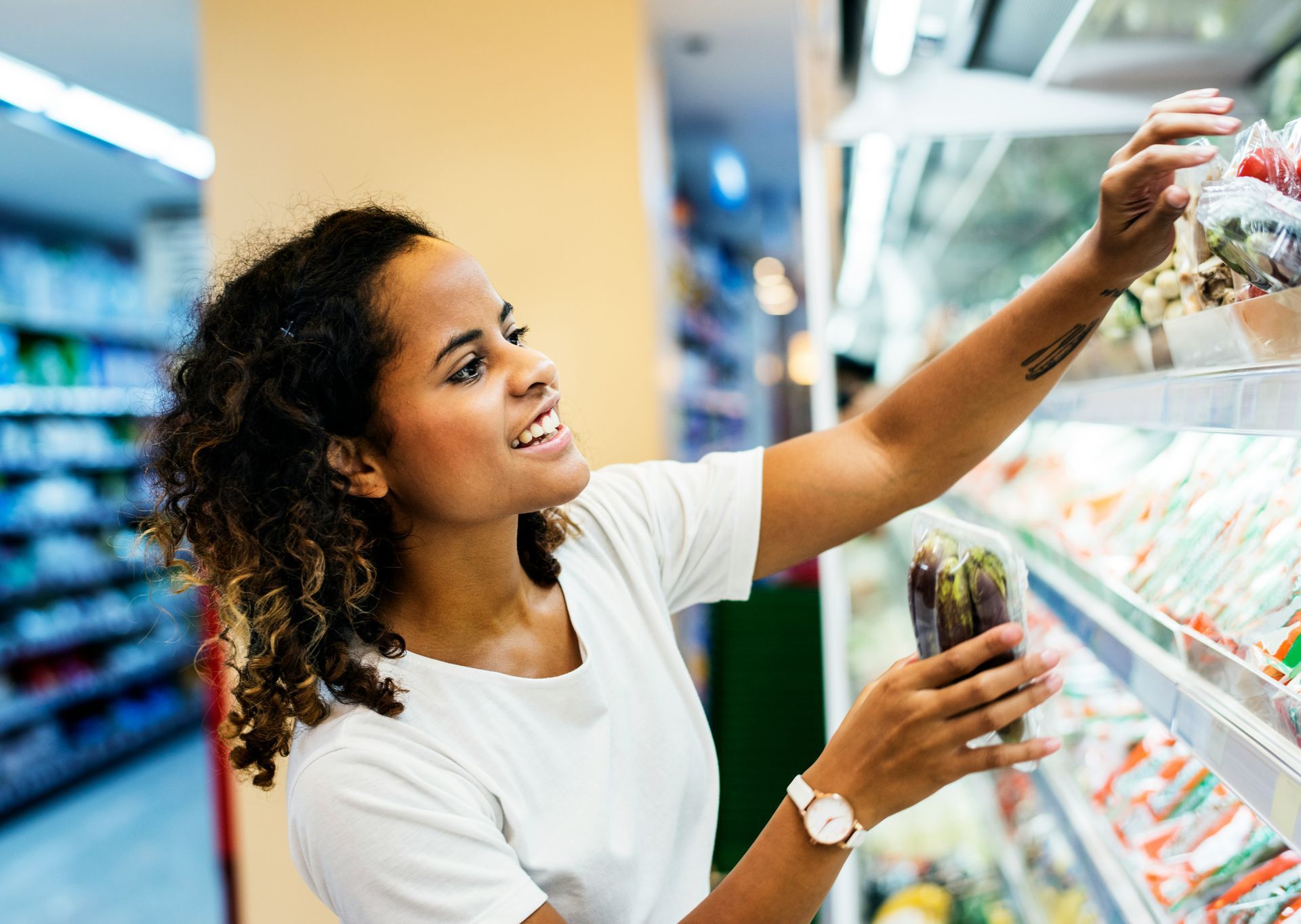 A woman is standing in a grocery store looking at food on a shelf.