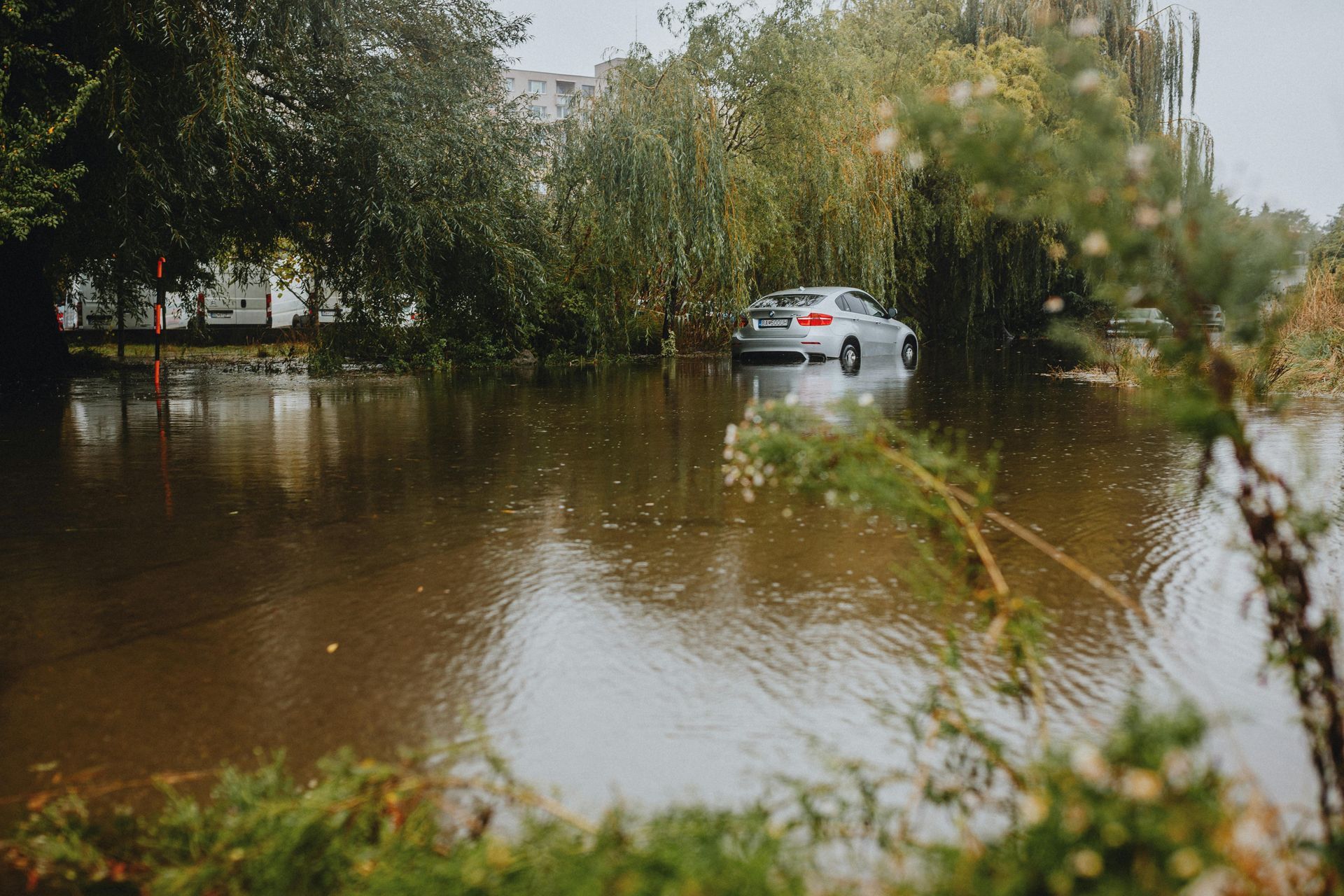 A car is floating in a flooded river.