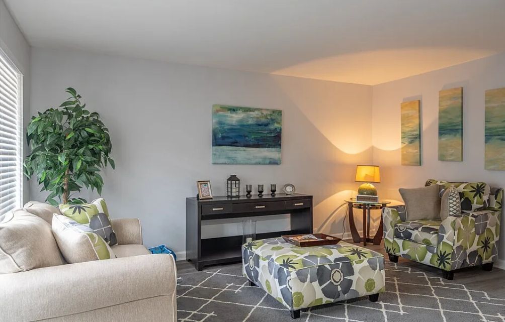 Photo of a living room with a chair and a small couch, as well as othe ritems