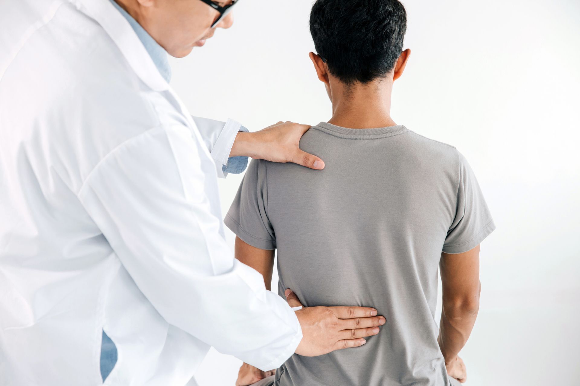 A doctor is examining a man 's back.