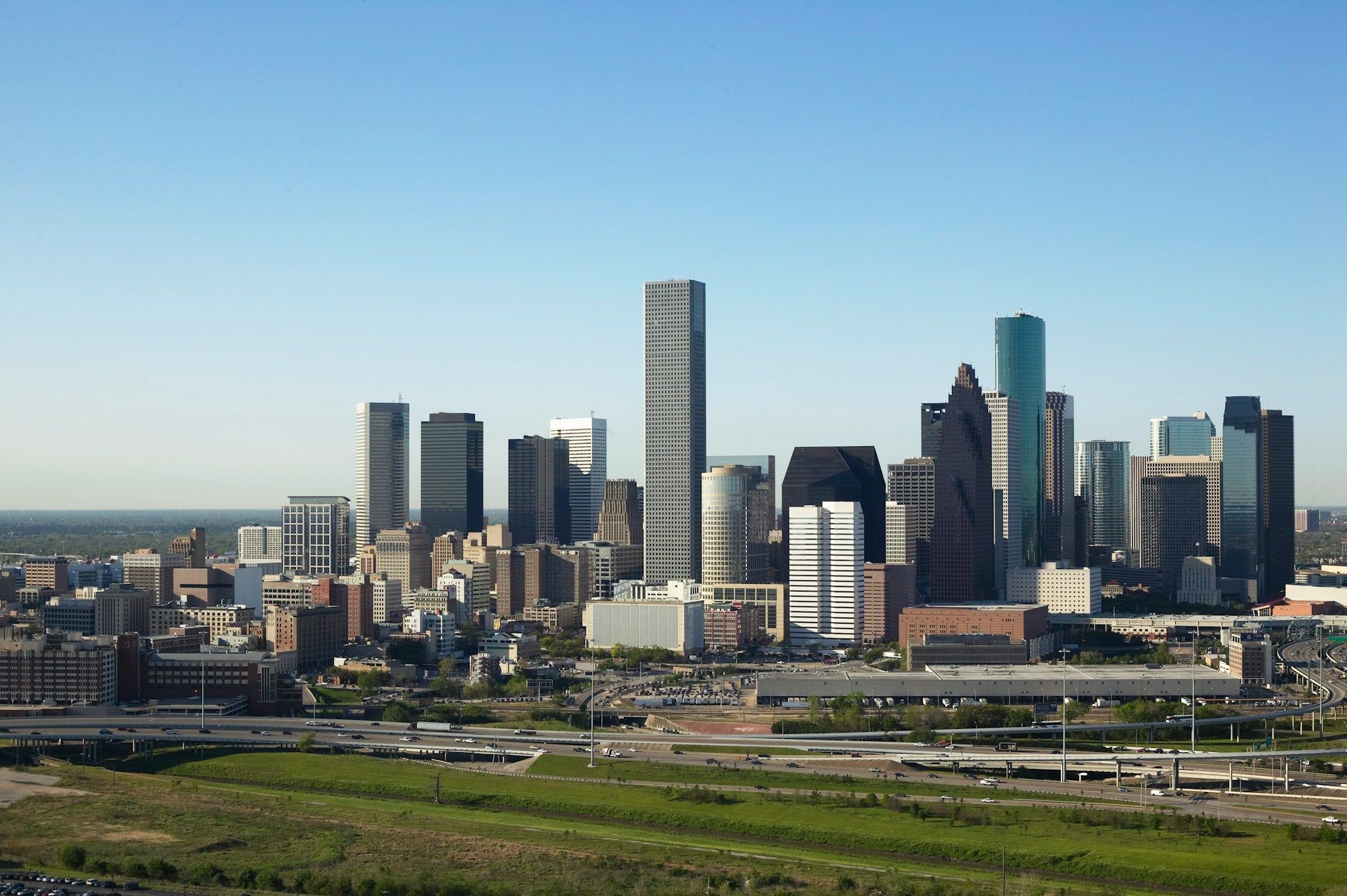 Skyline of buildings under a clear blue sky, with a tall, modern skyscraper prominent in the center.