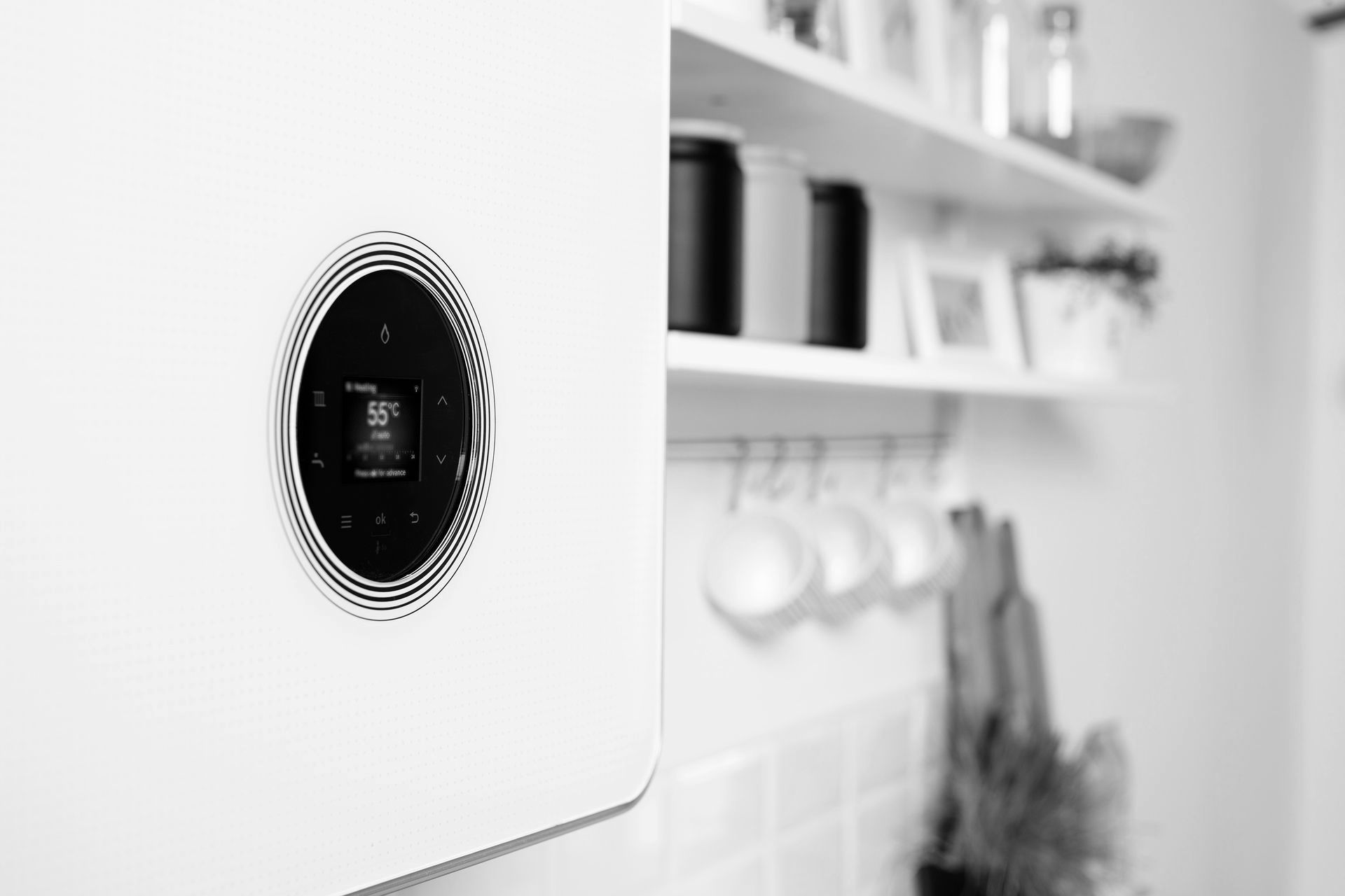 A black and white photo of a thermostat on a wall in a kitchen.
