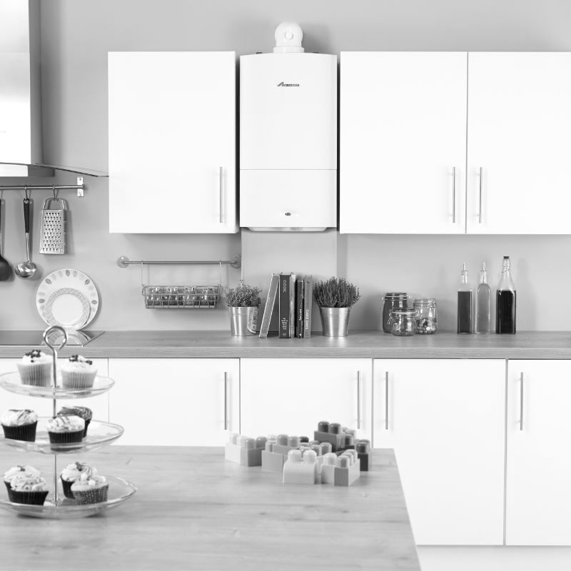 A black and white photo of a kitchen with white cabinets and a stove.