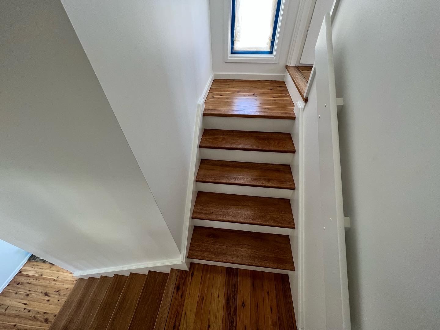 Wooden stairs leading up with white walls and a skylight at the top — LD Carpentry in Goulburn, NSW