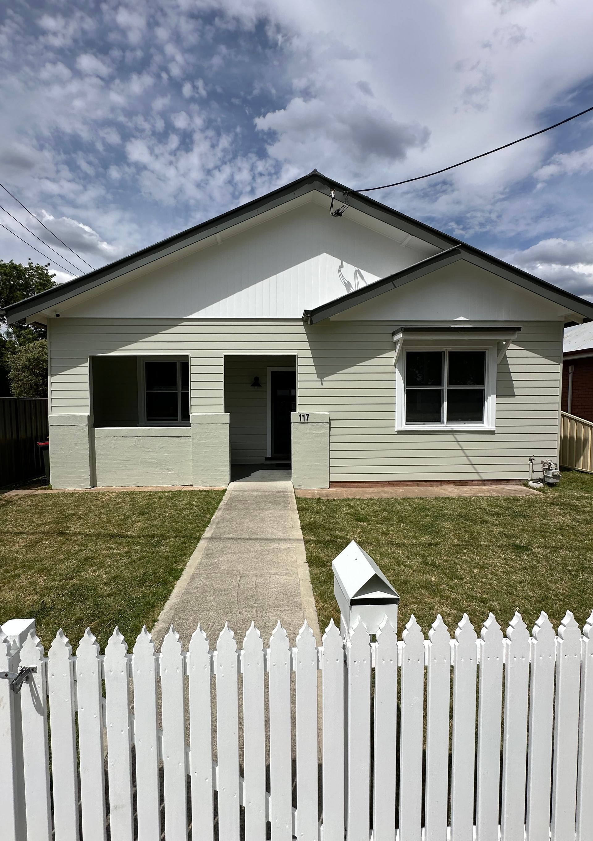 White house with a picket fence, light green exterior, blue sky — LD Carpentry in Goulburn, NSW