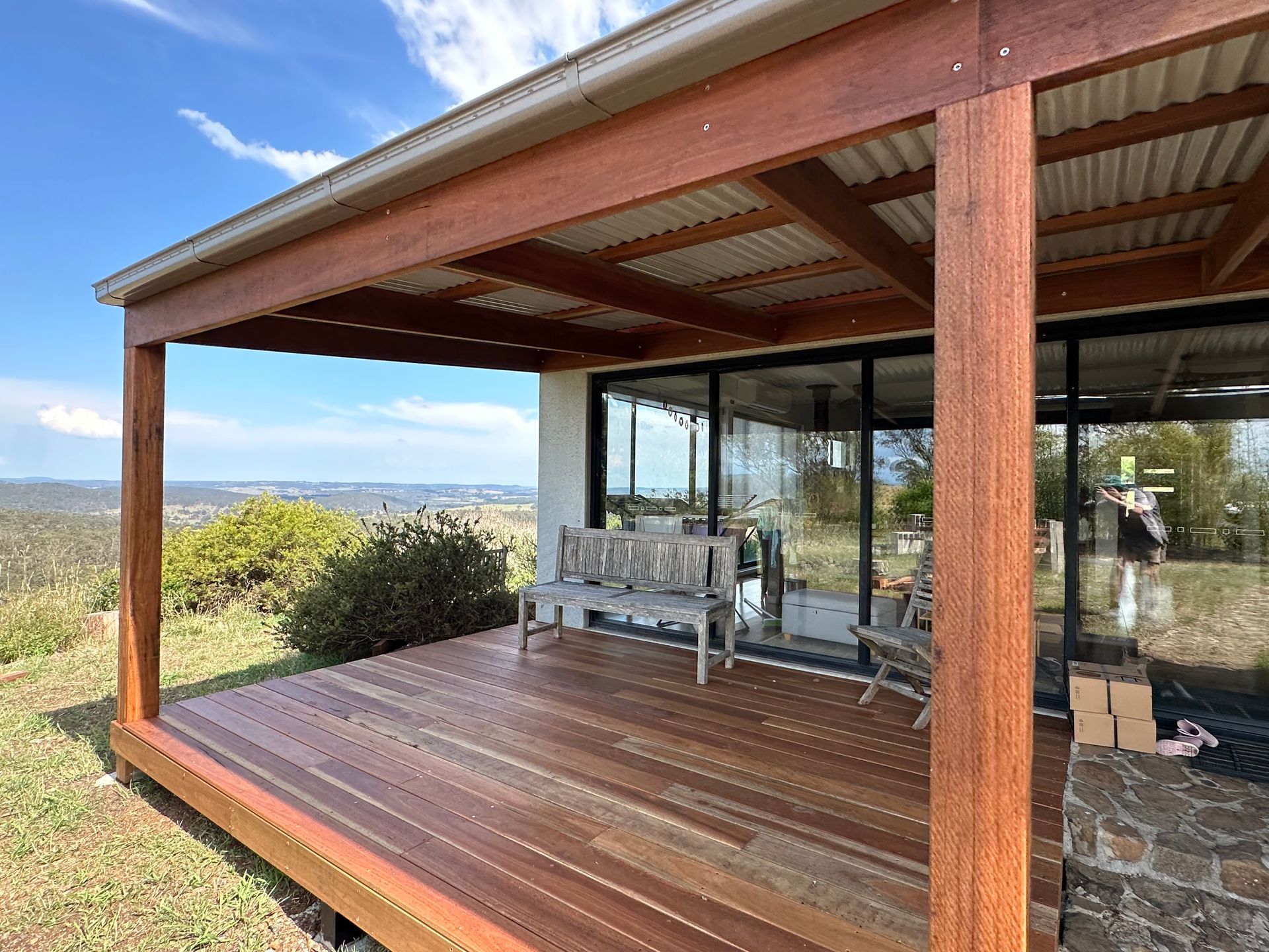 Wooden deck with a covered patio overlooking a scenic landscape and a bench — LD Carpentry in Goulburn, NSW