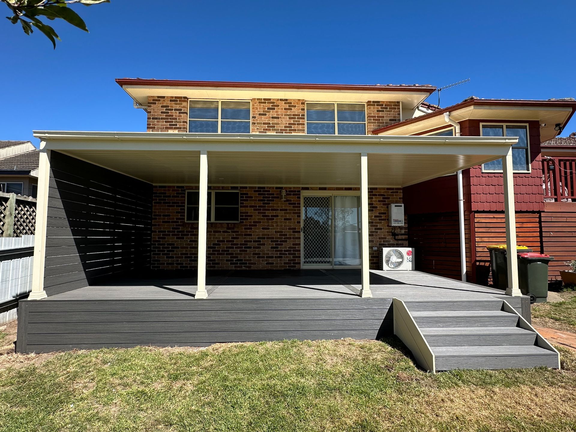 Backyard deck with covered patio, steps, and two-story brick home in the background — LD Carpentry in Goulburn, NSW