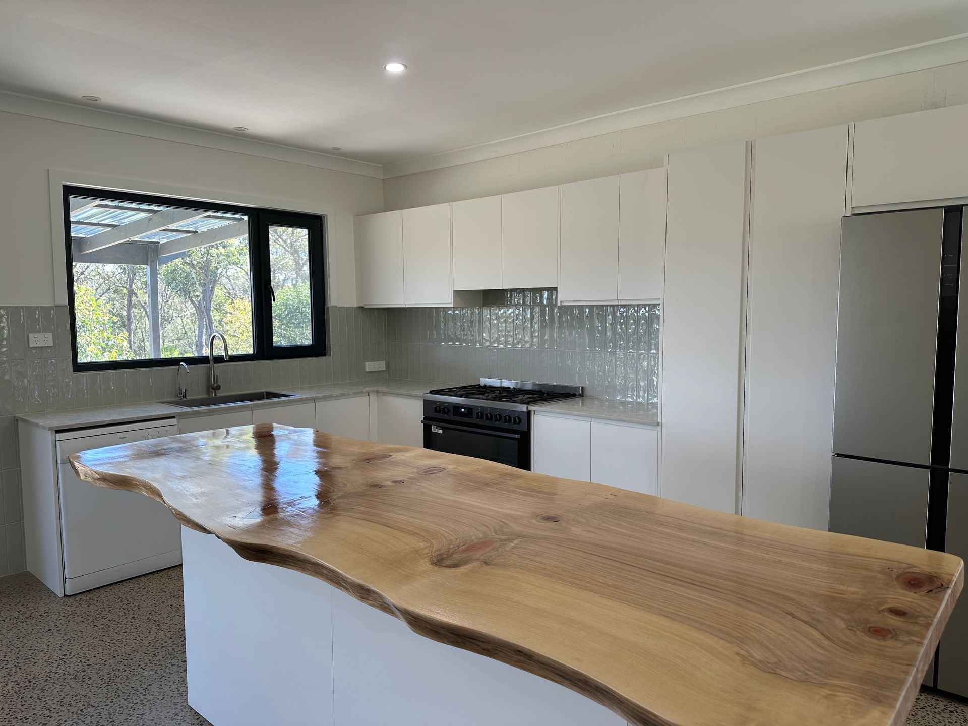 Kitchen with white cabinets, a live-edge wooden island, and a black stove — LD Carpentry in Goulburn, NSW