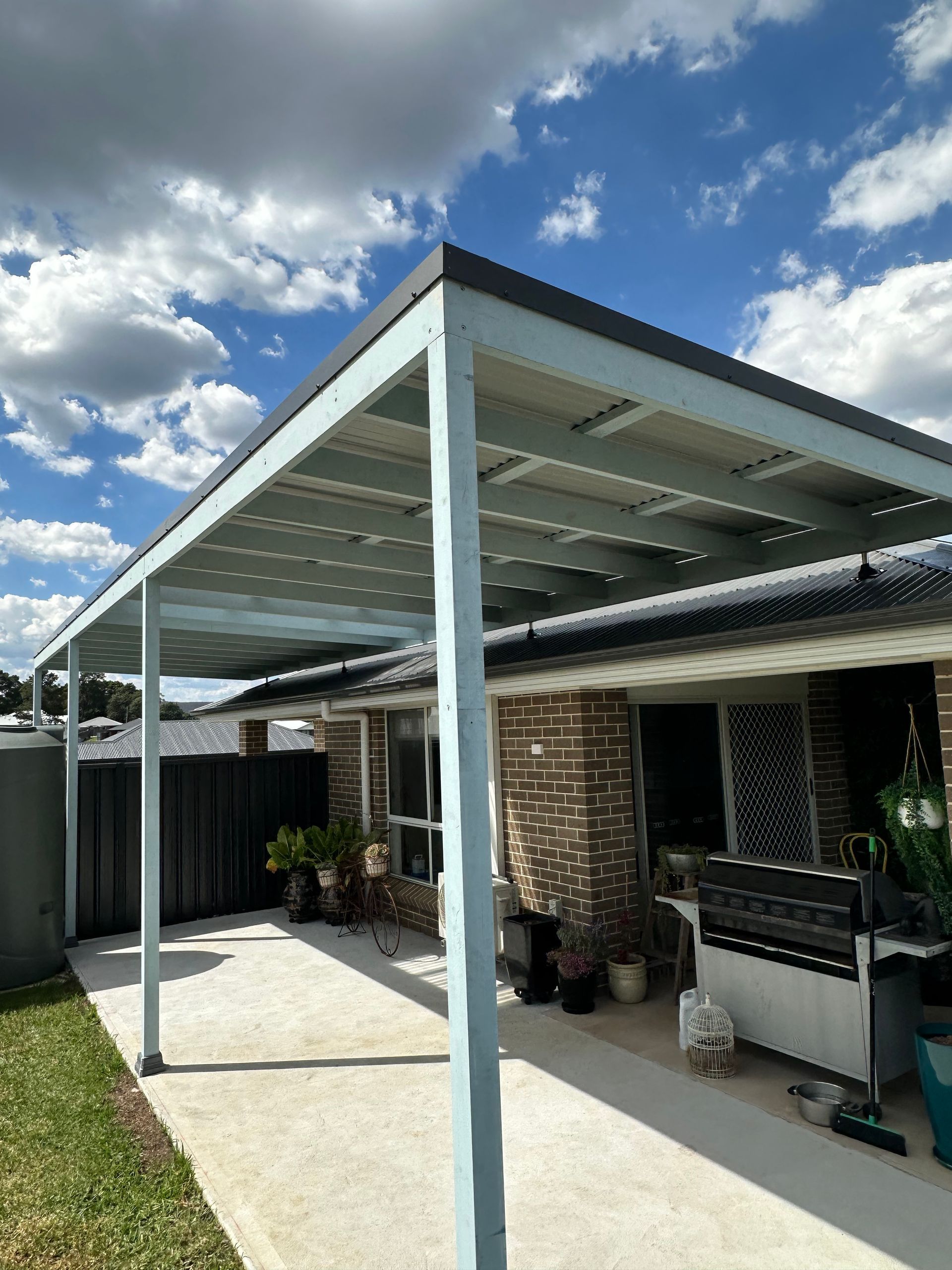 Pergola attached to a brick house with a concrete patio, against a cloudy sky — LD Carpentry in Goulburn, NSW