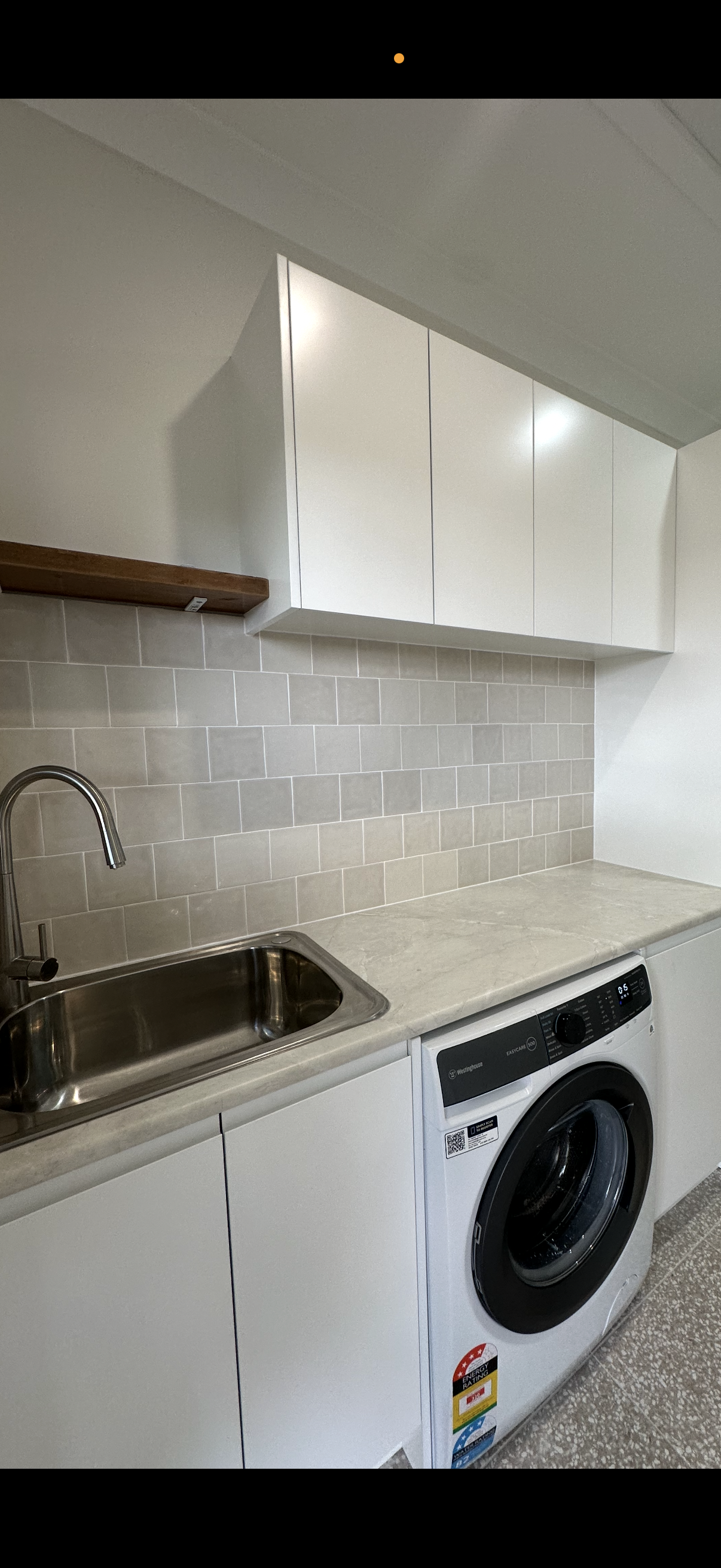 Laundry room with white cabinets, grey tile backsplash, stainless sink, and washing machine LD Carpentry in Goulburn, NSW