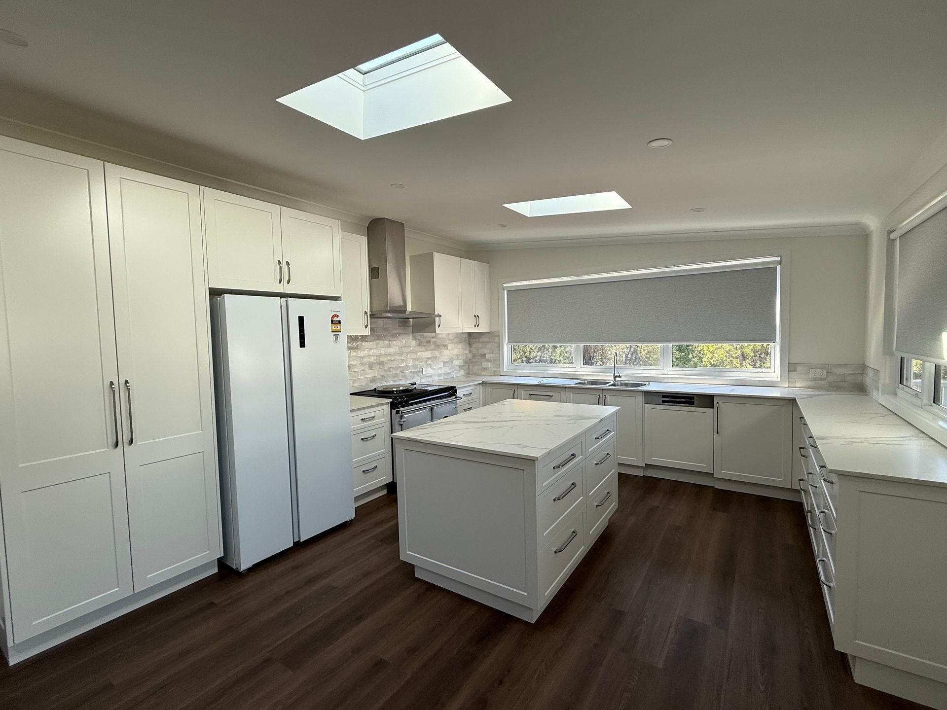 White kitchen with island, cabinets, stainless steel appliances, and two skylights — LD Carpentry in Goulburn, NSW