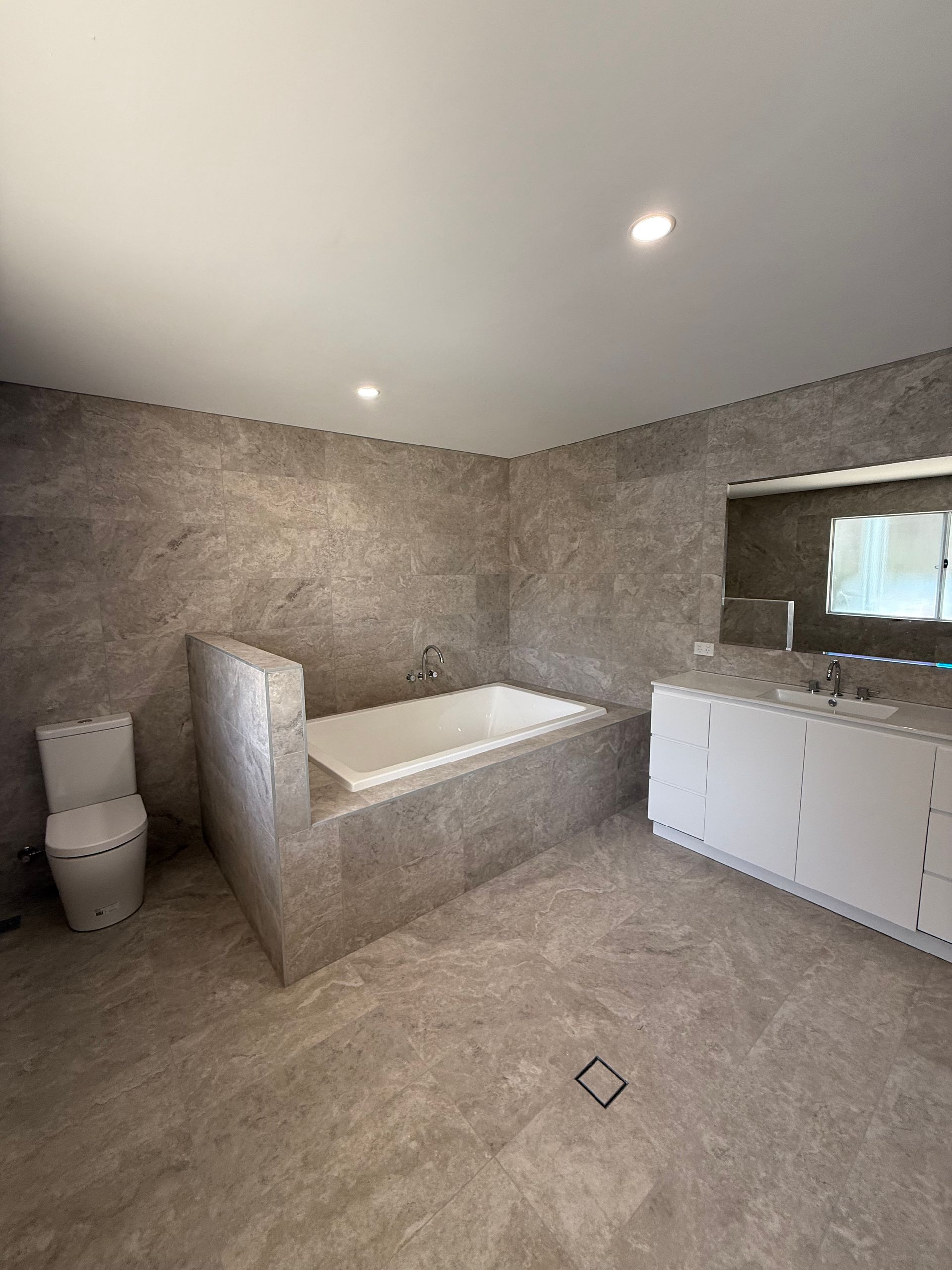 Modern bathroom with gray tile walls and flooring — LD Carpentry in Goulburn, NSW