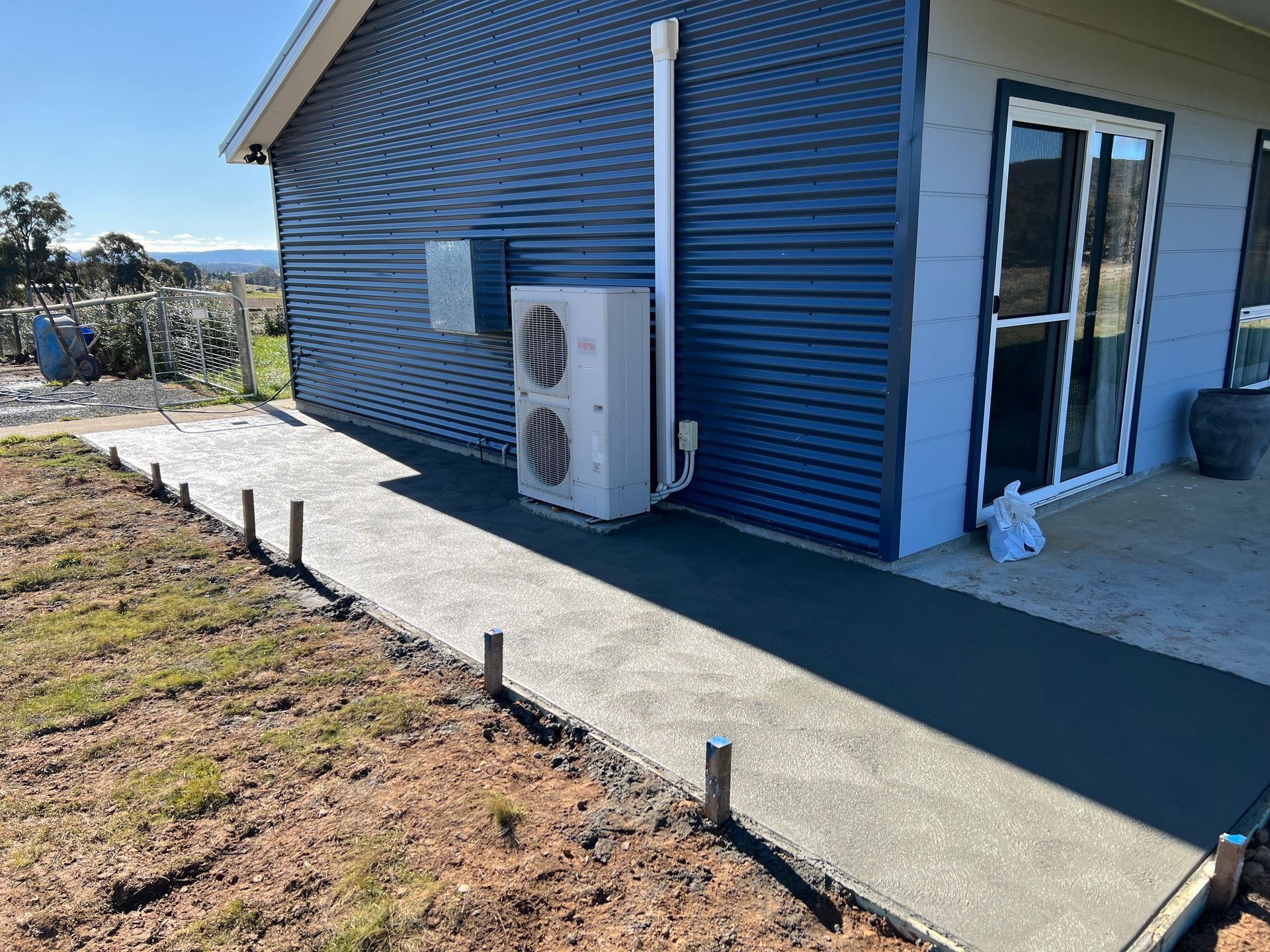 Concrete walkway alongside a blue house with an air conditioning unit — LD Carpentry in Goulburn, NSW