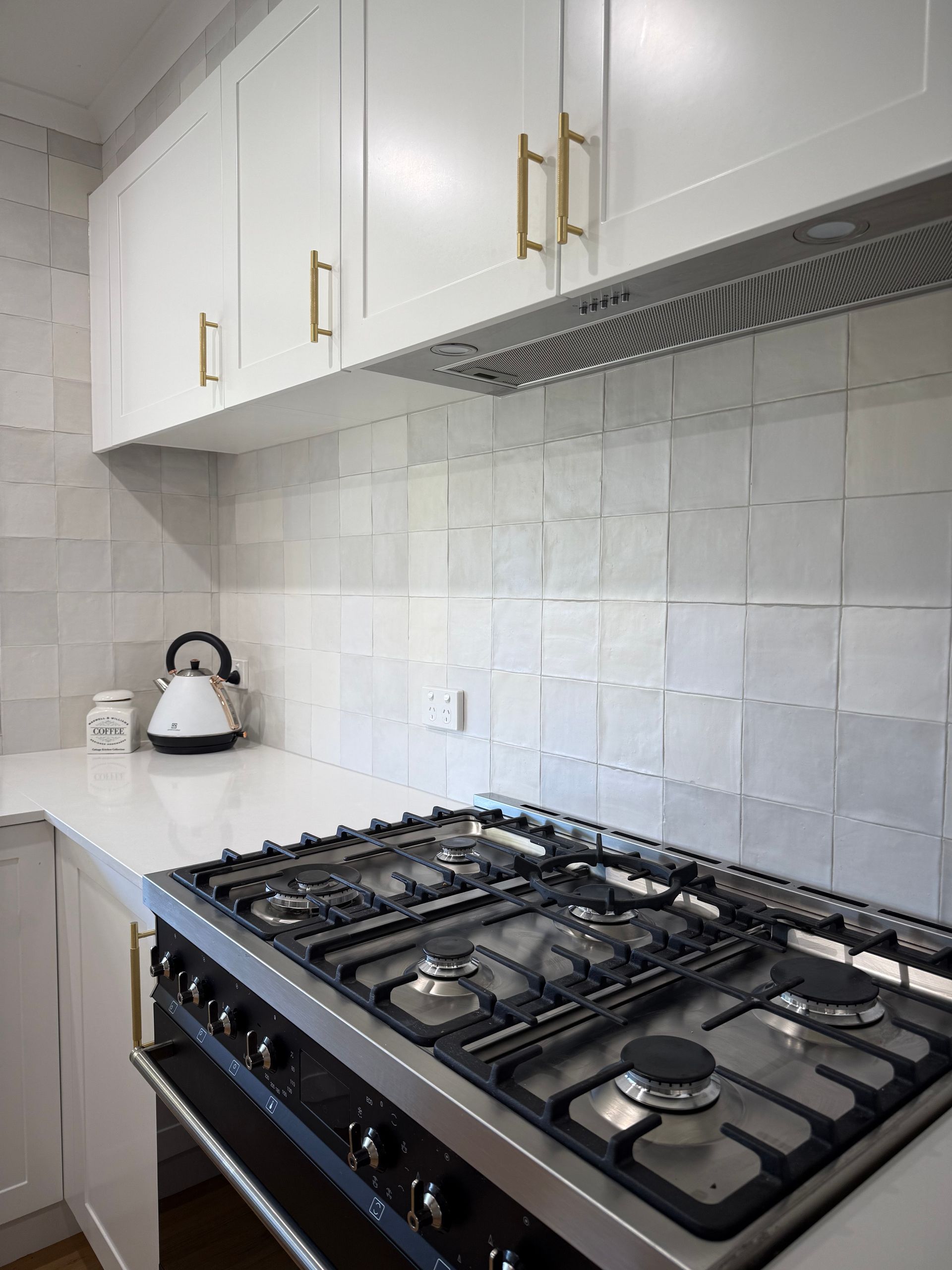 White kitchen with stove, cabinets, and backsplash.