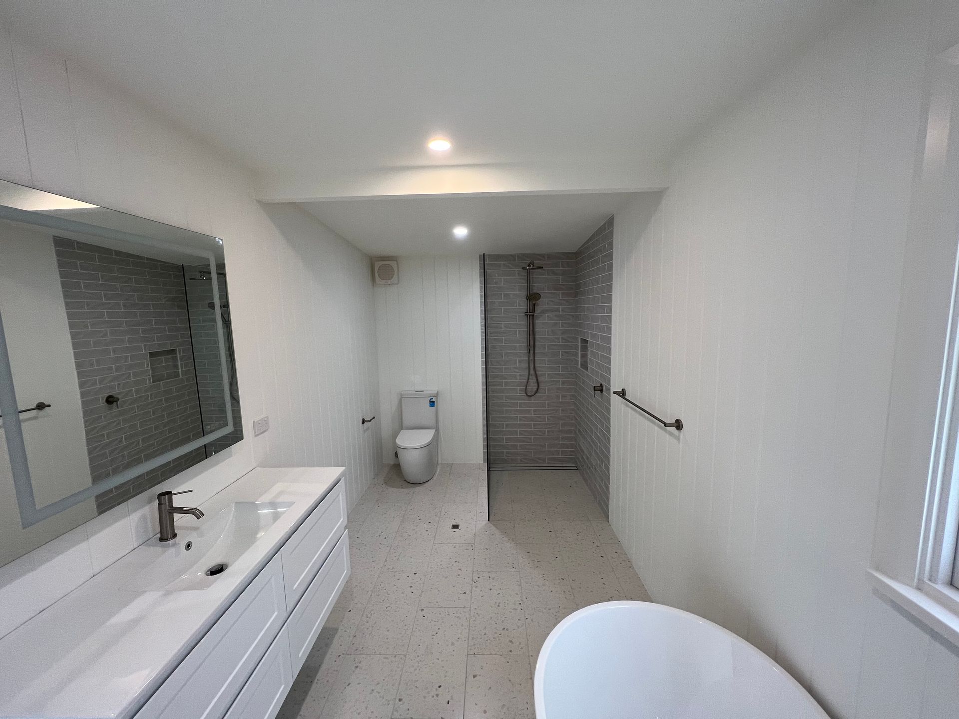 Modern white bathroom with a vanity, toilet, shower, and tub — LD Carpentry in Goulburn, NSW