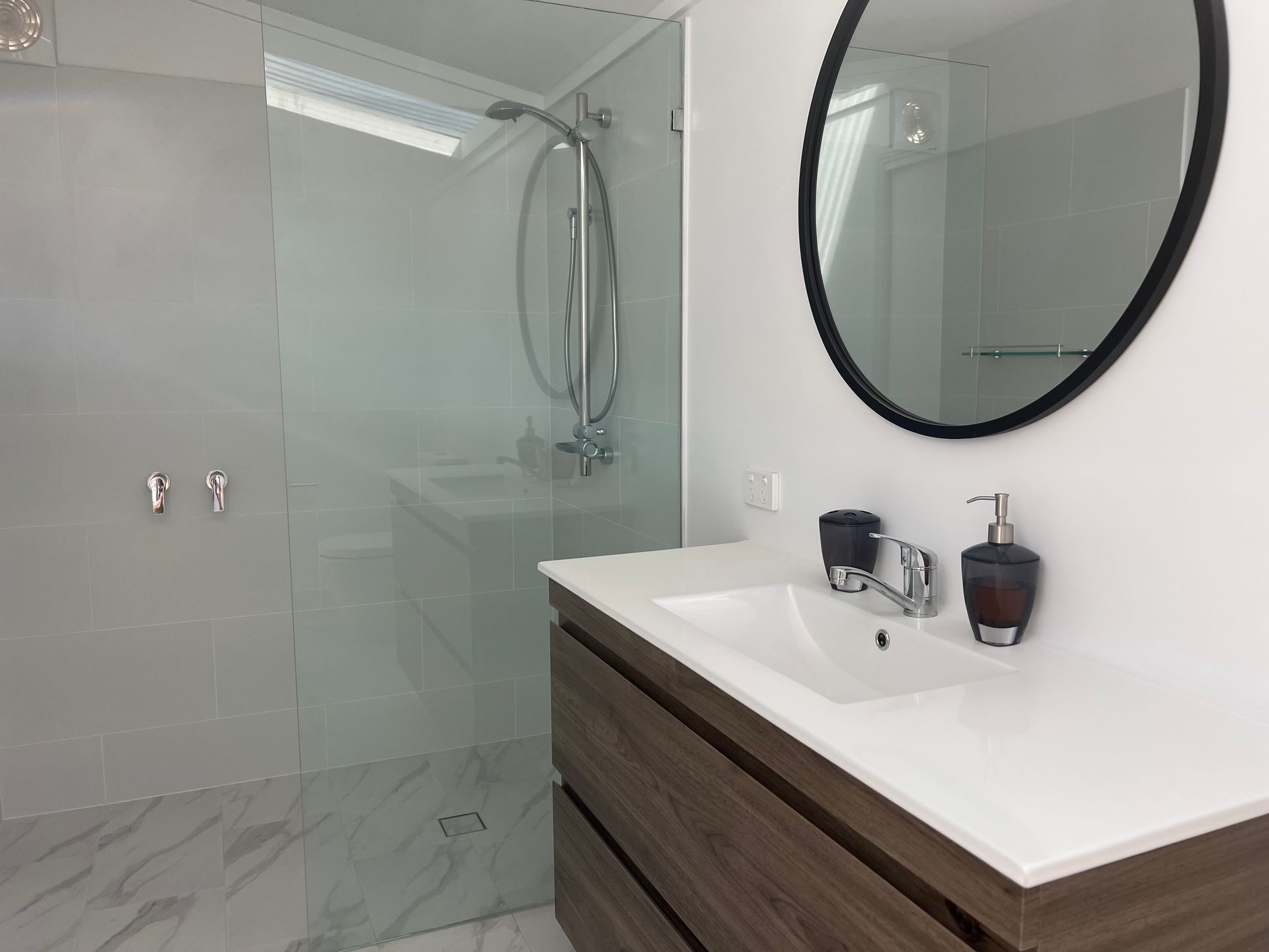 Modern bathroom with shower, vanity, and round mirror — LD Carpentry in Goulburn, NSW