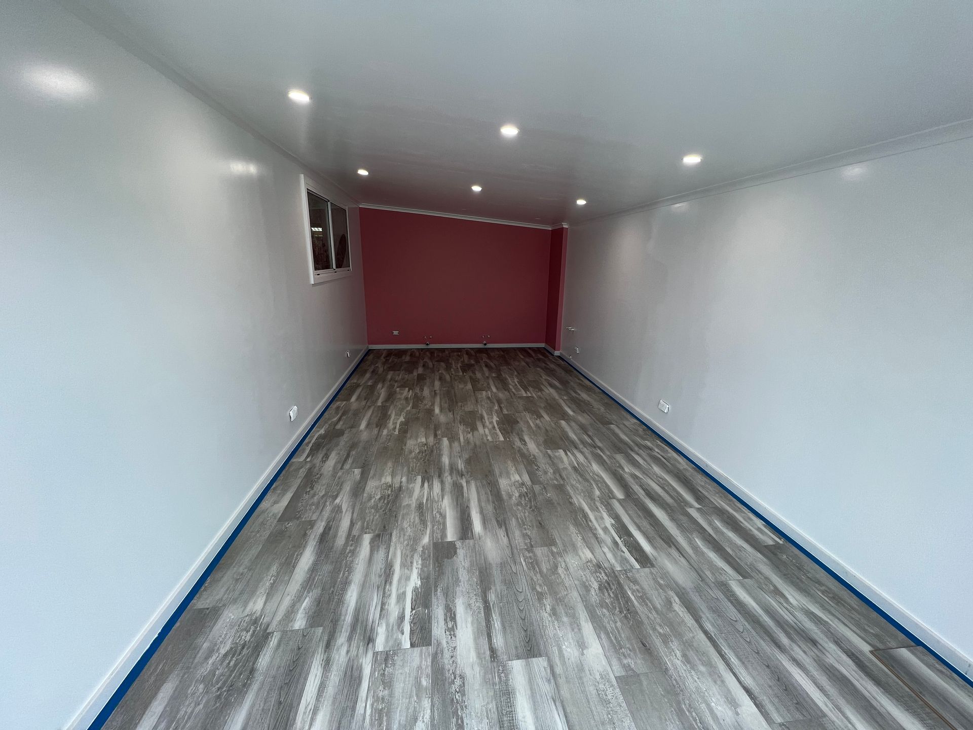 Empty room with gray flooring, white walls, and a reddish-pink accent wall — LD Carpentry in Goulburn, NSW