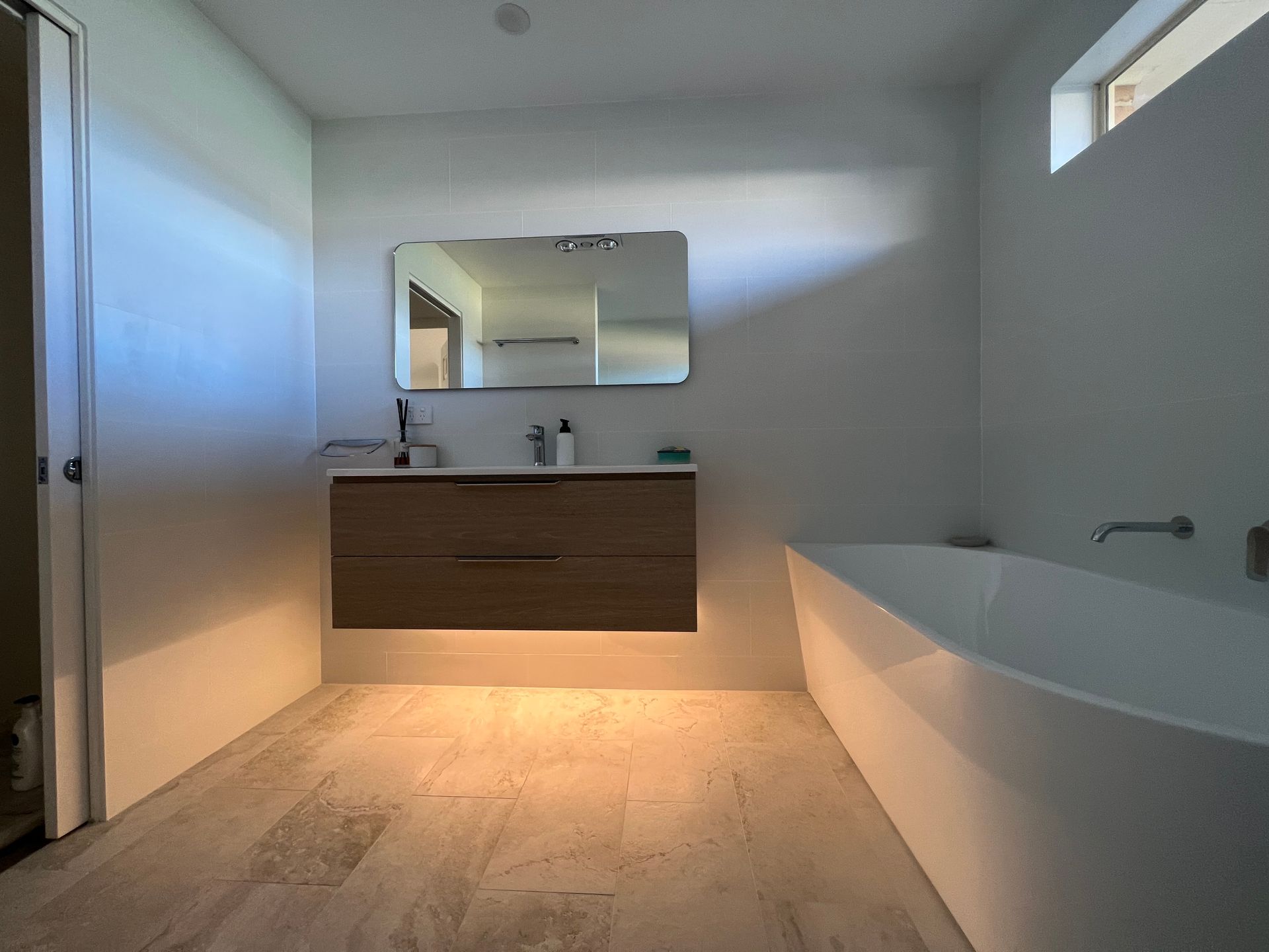 Modern bathroom with wood vanity, large mirror, and white bathtub — LD Carpentry in Goulburn, NSW