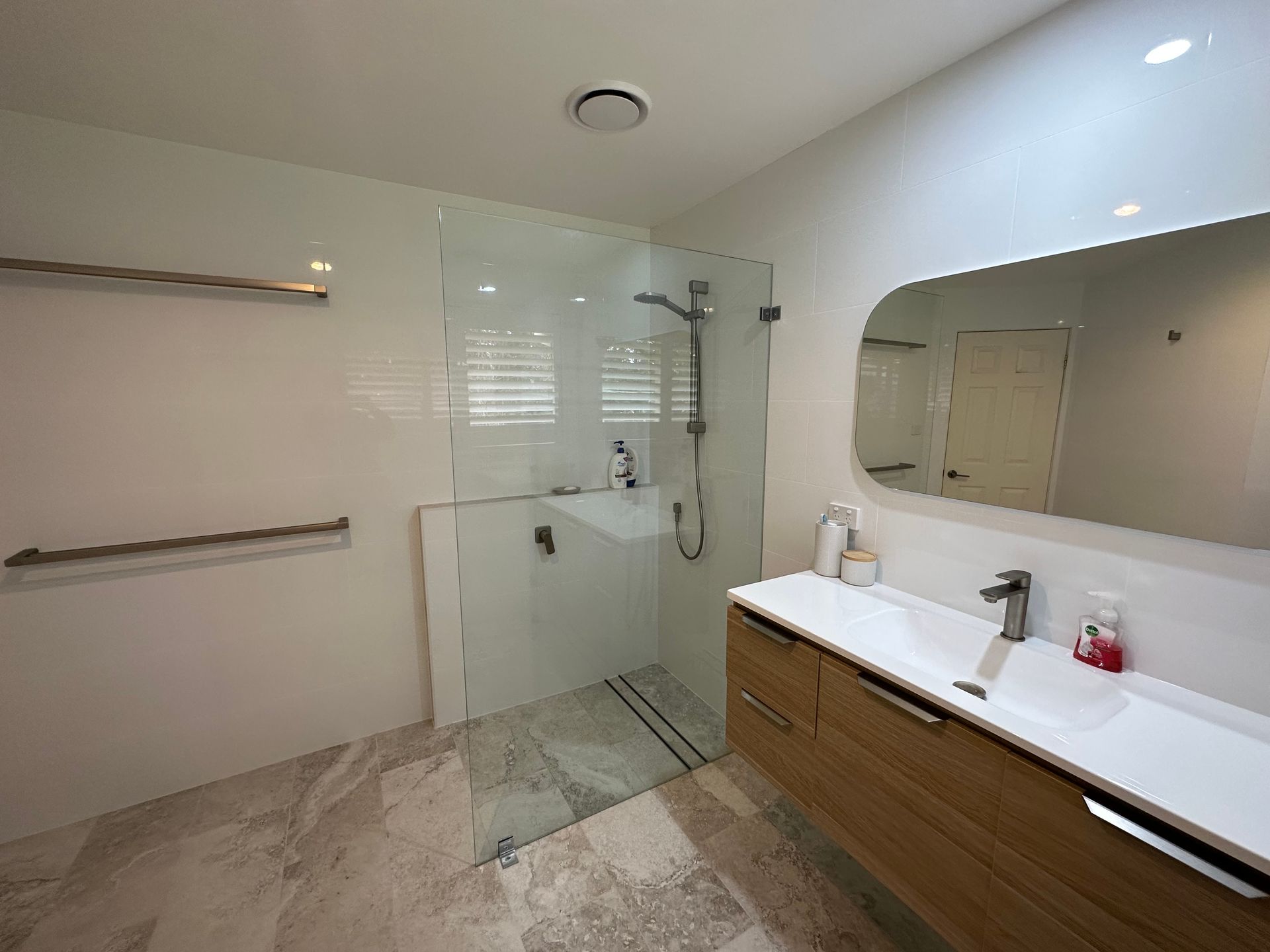 Modern bathroom with glass shower, wooden vanity, large mirror, and tiled floor — LD Carpentry in Goulburn, NSW