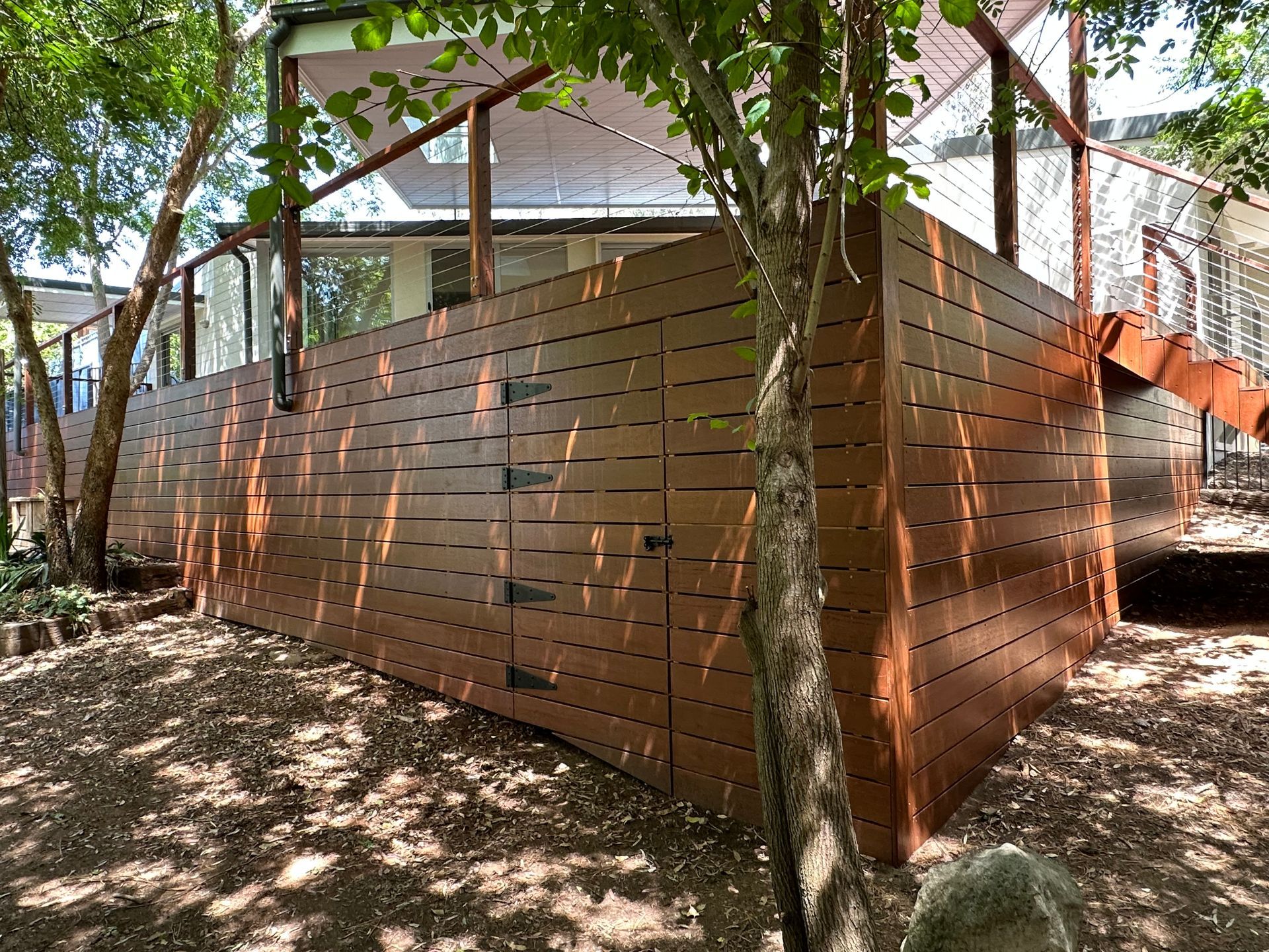 Brown wooden fence with access doors in a yard with trees — LD Carpentry in Goulburn, NSW