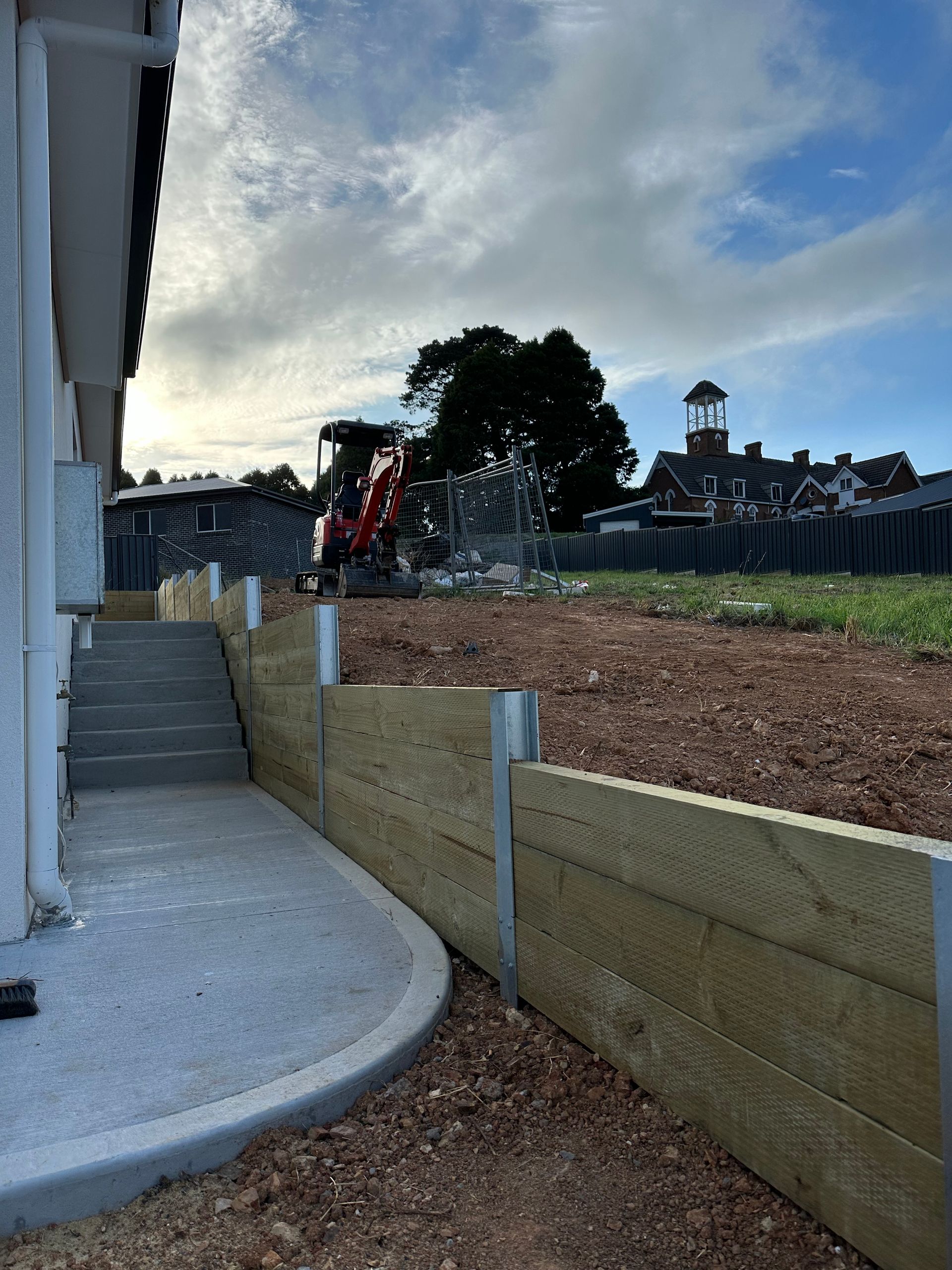 A retaining wall with stairs next to a house under construction — LD Carpentry in Goulburn, NSW