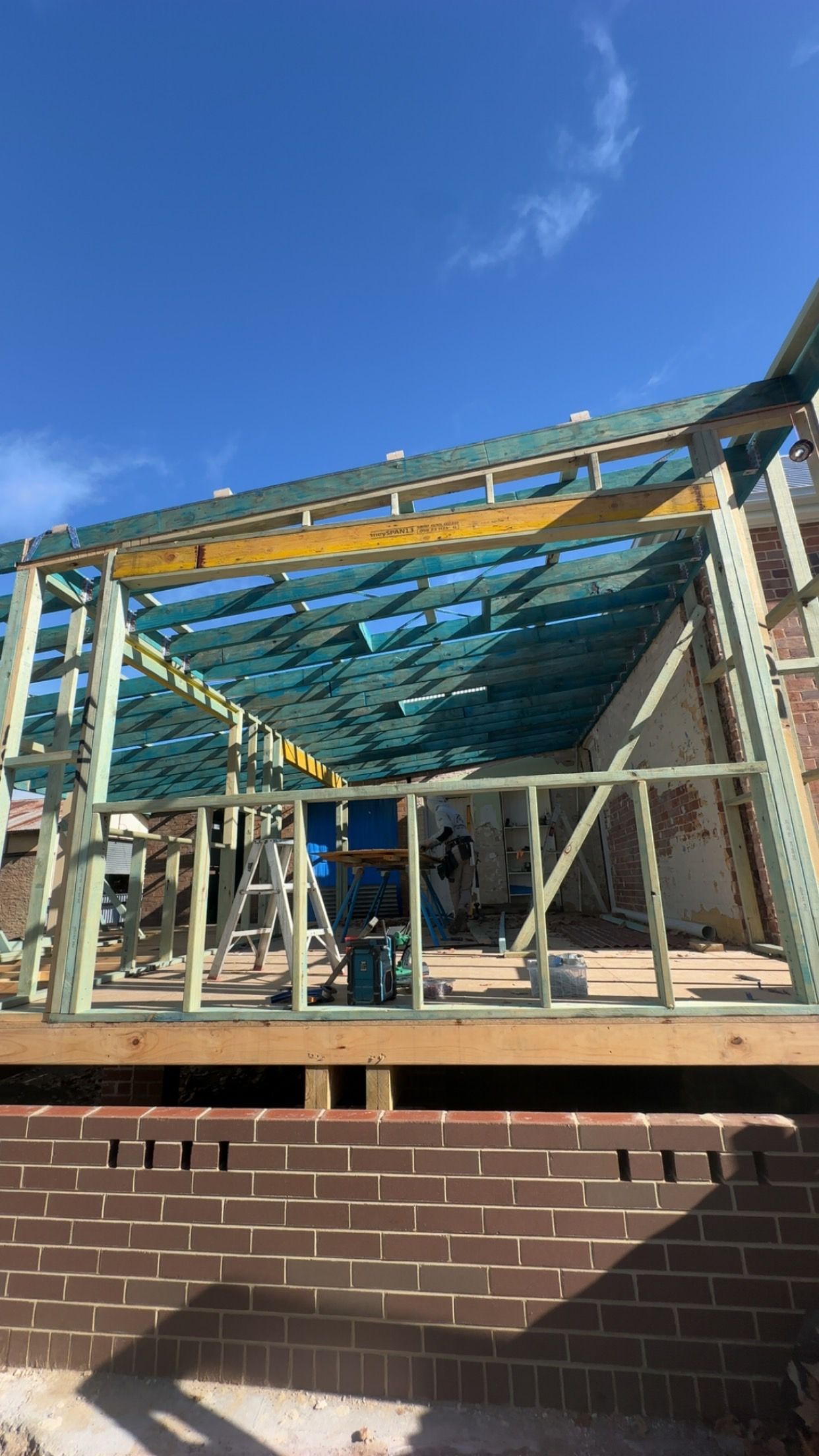 Brick building under construction, with wooden frame roof and supports against a blue sky — LD Carpentry in Goulburn, NSW