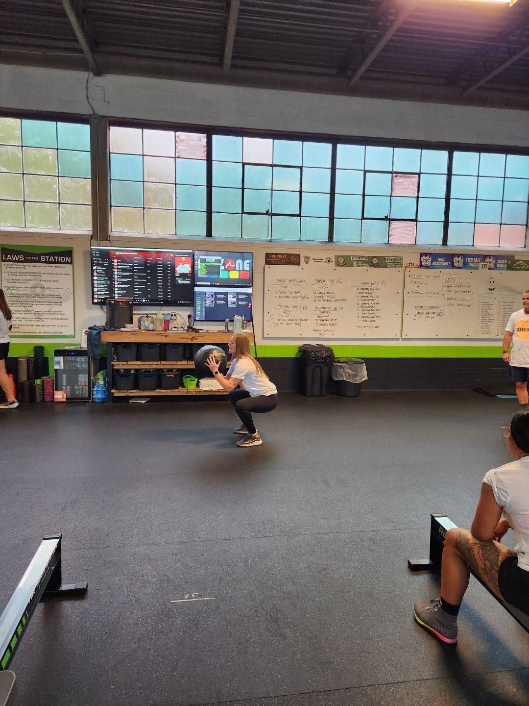 A group of people are squatting in a gym.