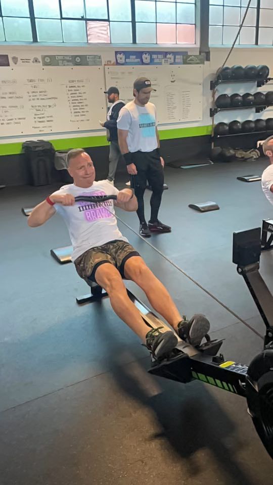 A man is rowing a rowing machine in a gym.