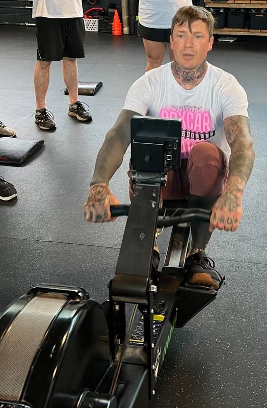 A man is riding a rowing machine in a gym.
