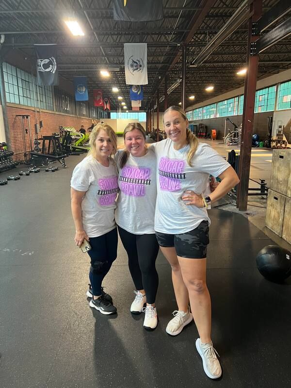 Three women are posing for a picture in a gym.