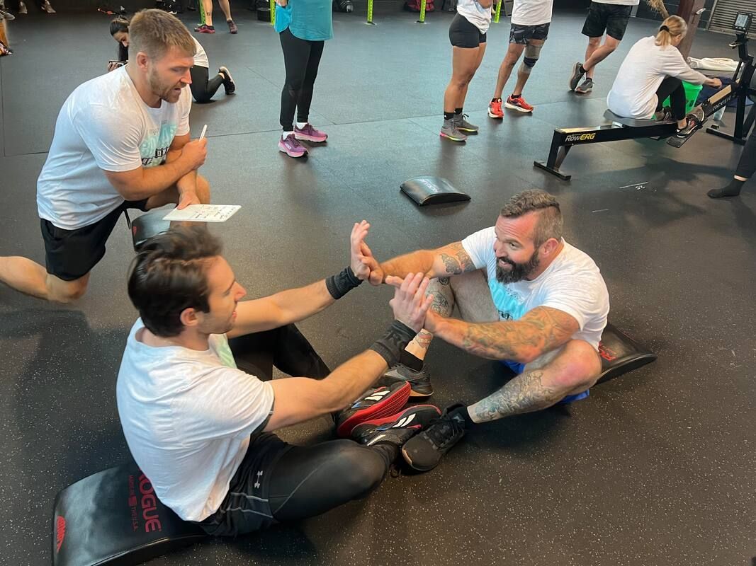 A group of men are sitting on the floor in a gym.