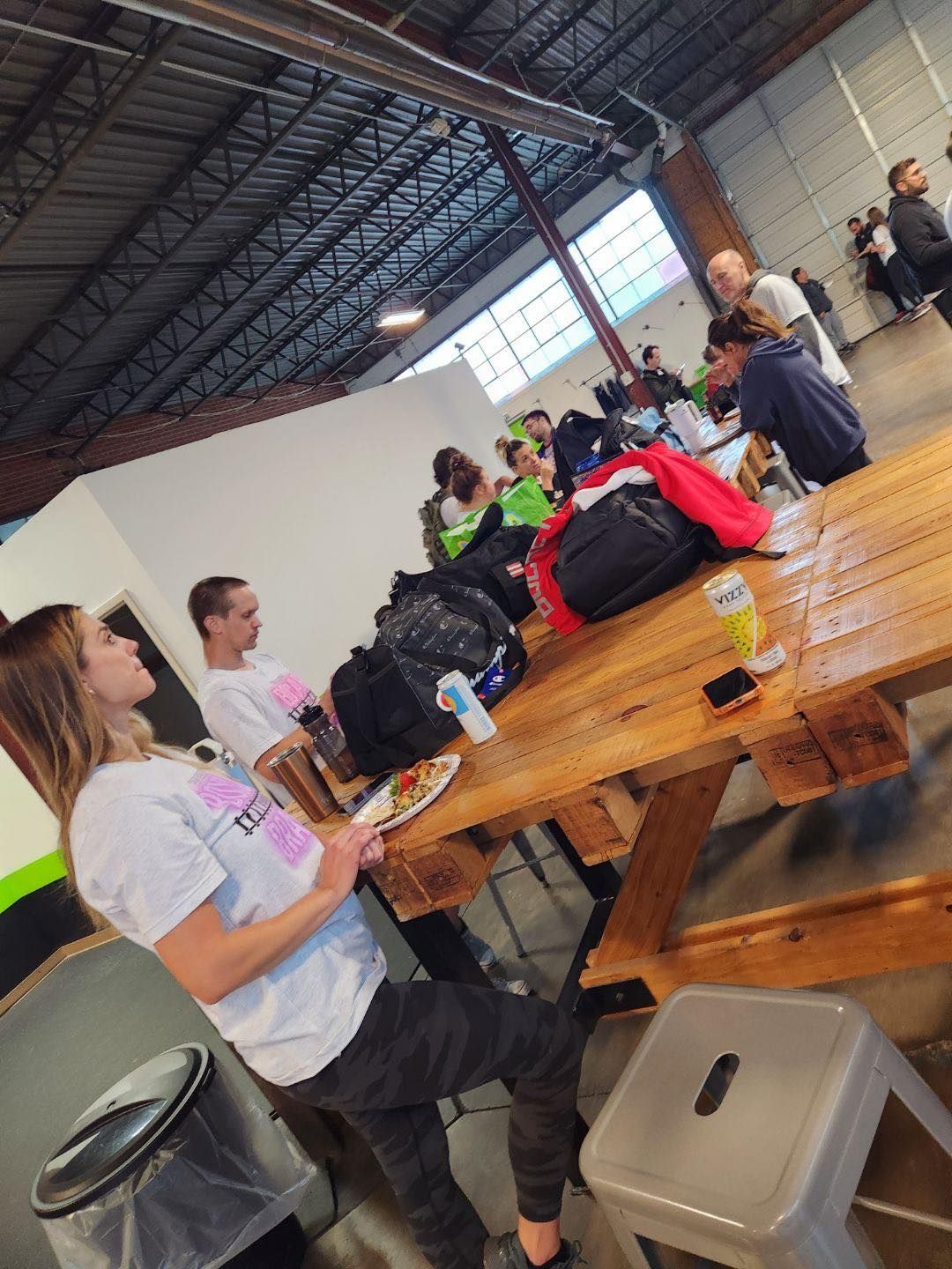 A group of people are sitting around a wooden picnic table.