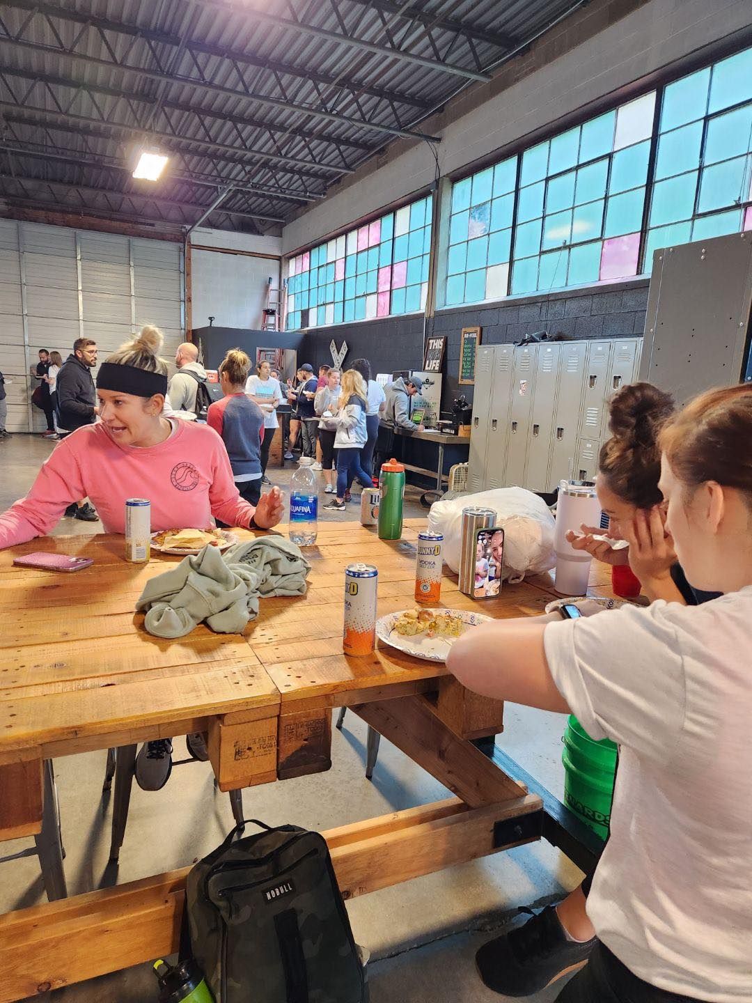 A group of people are sitting at a wooden picnic table eating food.