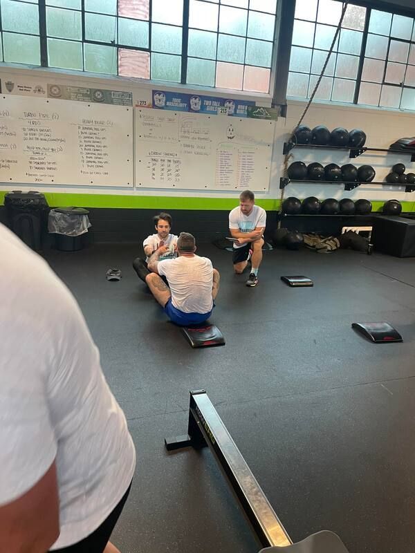 A group of people are sitting on the floor in a gym.