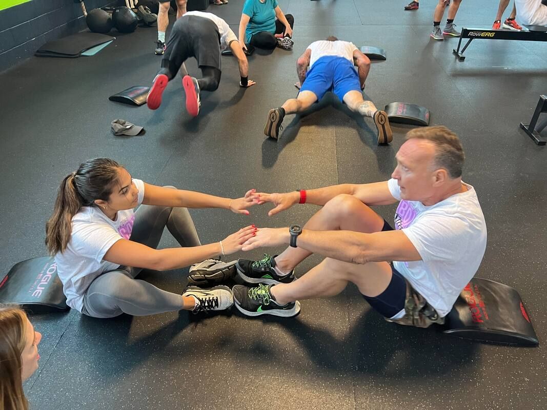 A group of people are doing exercises on the floor in a gym.