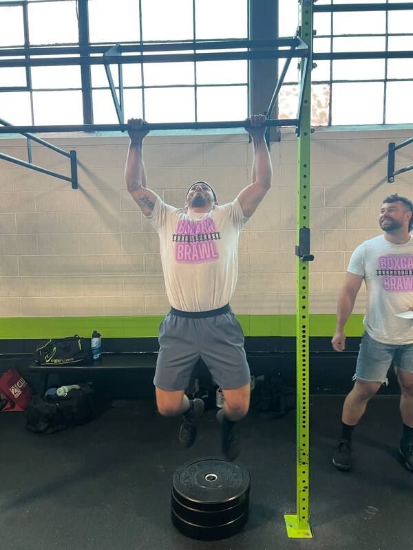 A man is doing a pull up on a bar in a gym.