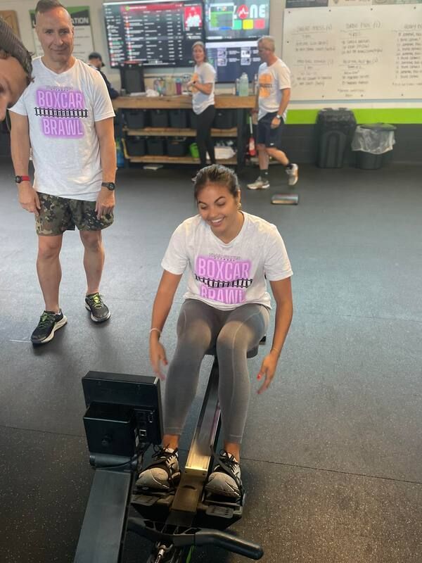 A woman is riding a rowing machine in a gym.