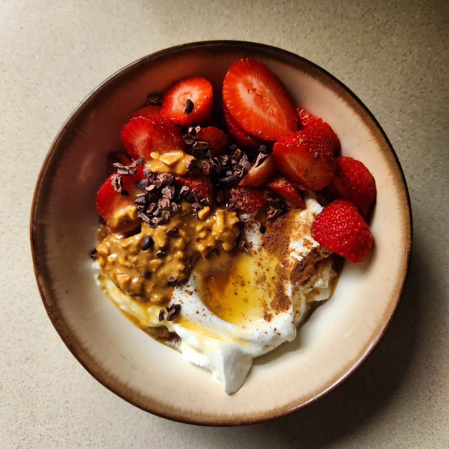 A bowl of food with strawberries peanut butter and whipped cream